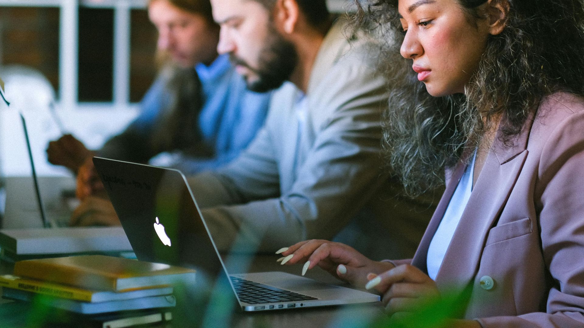 Concentrated young coworkers in formal wear working on modern netbooks and sitting at table in coworking space