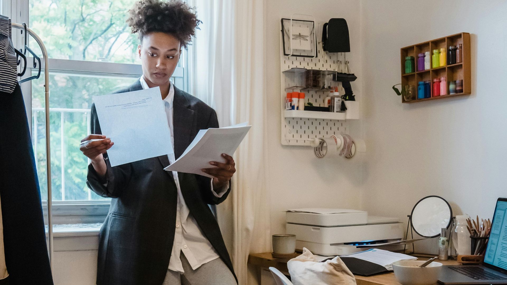 Young professional working remotely in a casual home setting with laptop and scattered clothing.