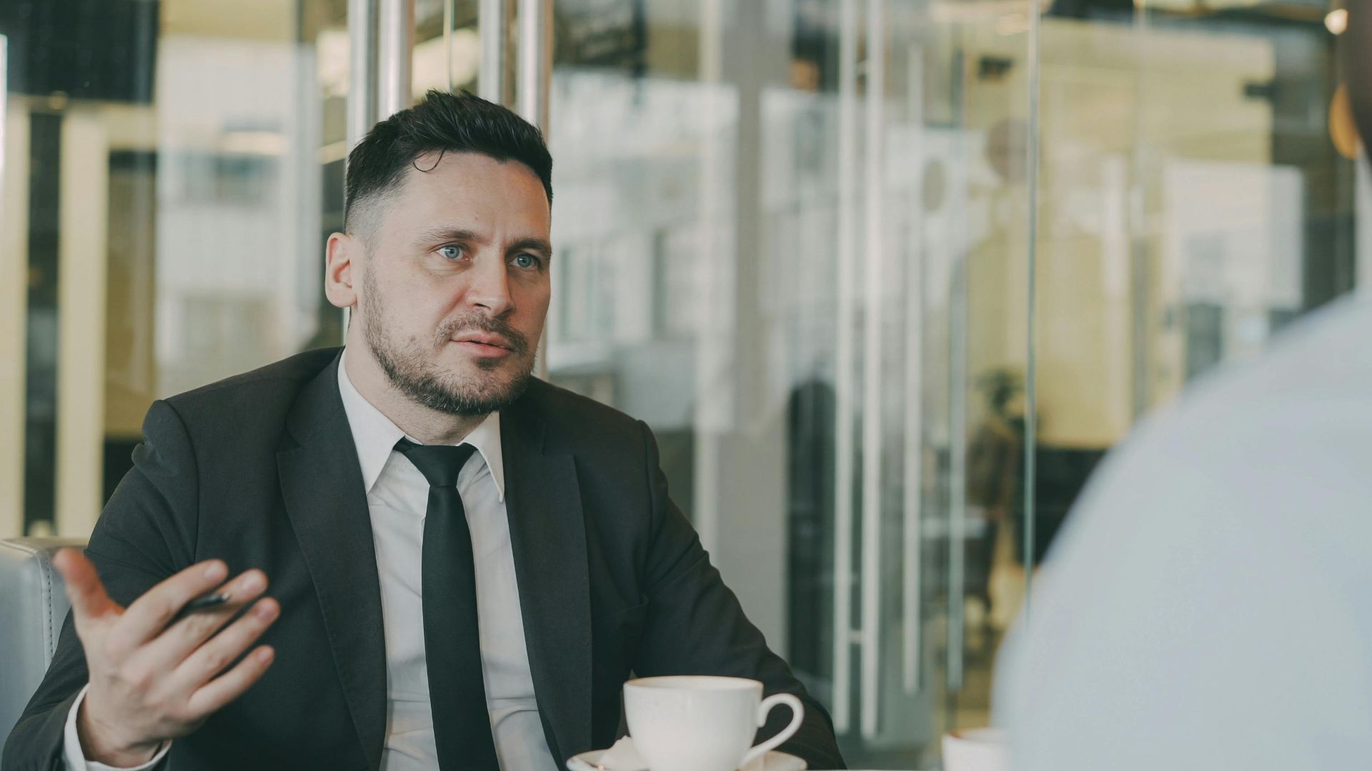 Two businessmen having a professional discussion over coffee in a modern cafe setting.