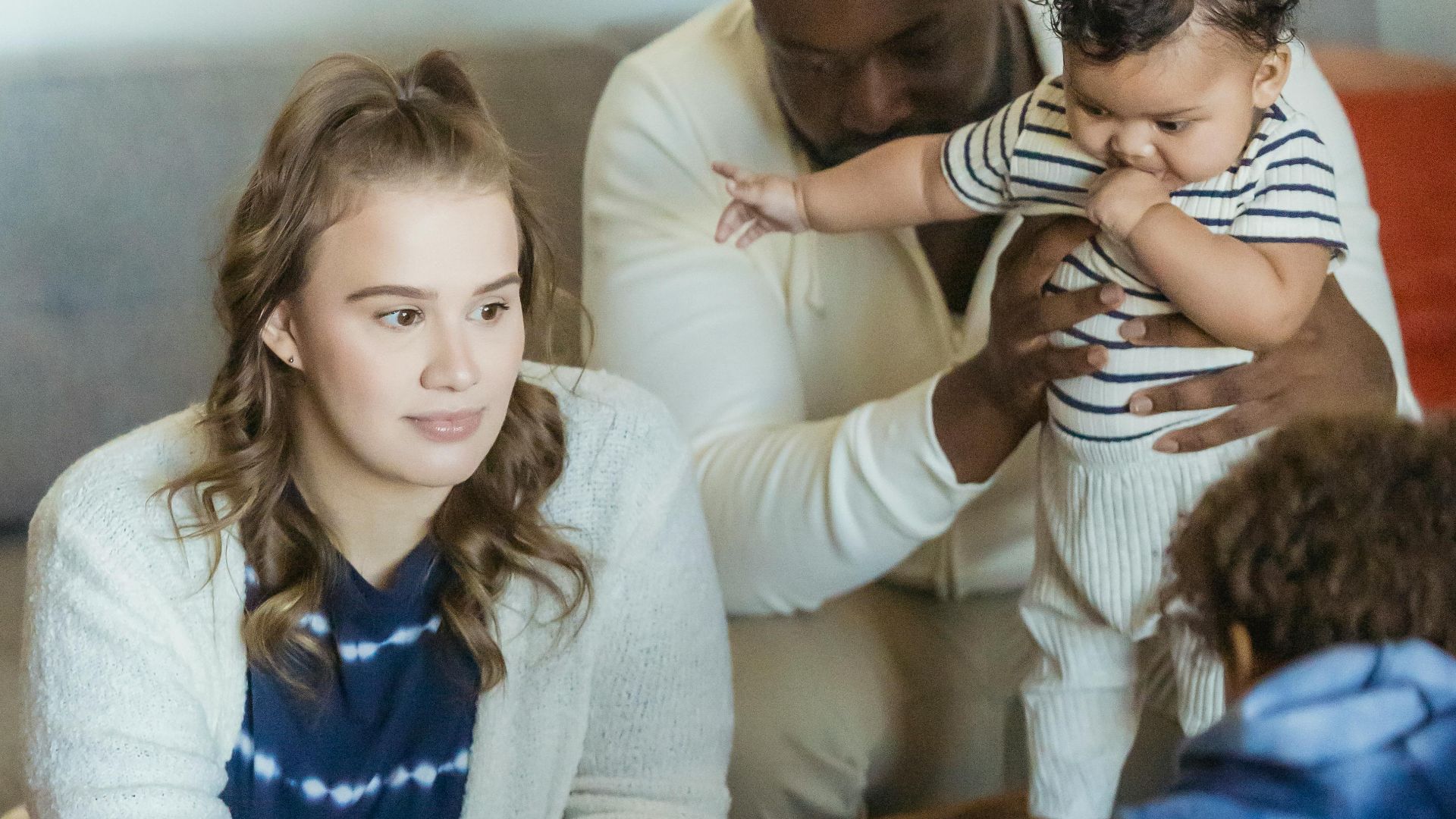 Crop anonymous boy playing with toy numbers against multiethnic parents with toddler kid at home