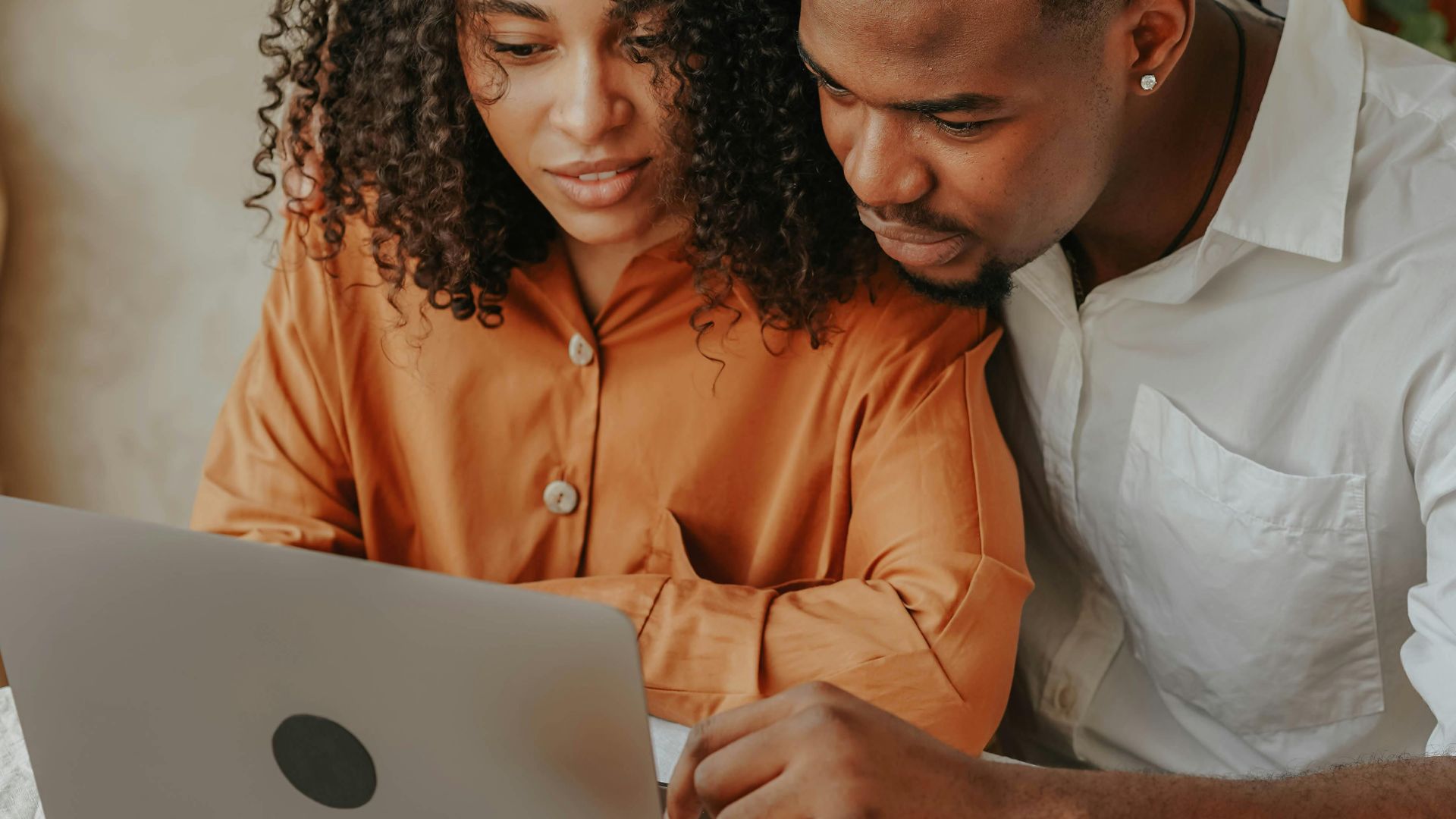 Young African American couple engaged with a laptop indoors, showing teamwork and connection.