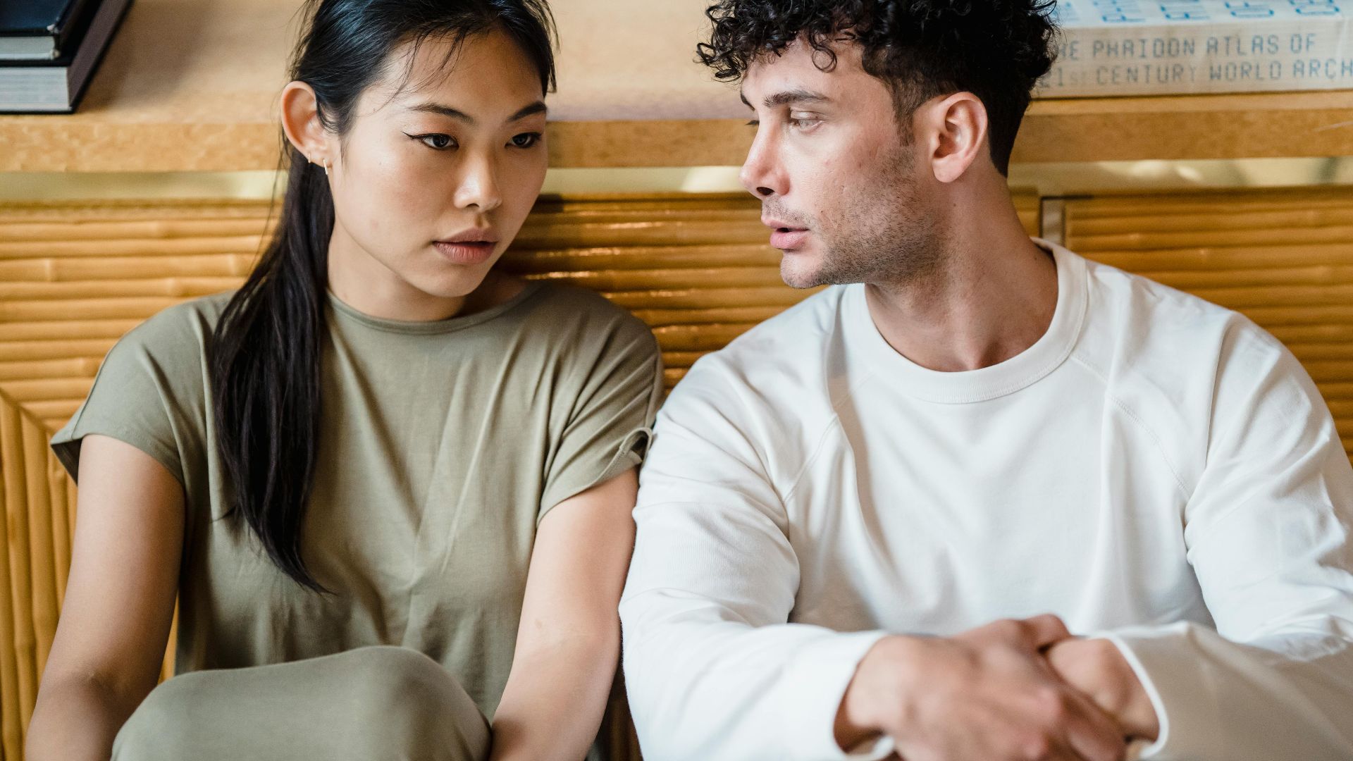 Asian woman and man sitting together having a serious conversation. Indoor setting.