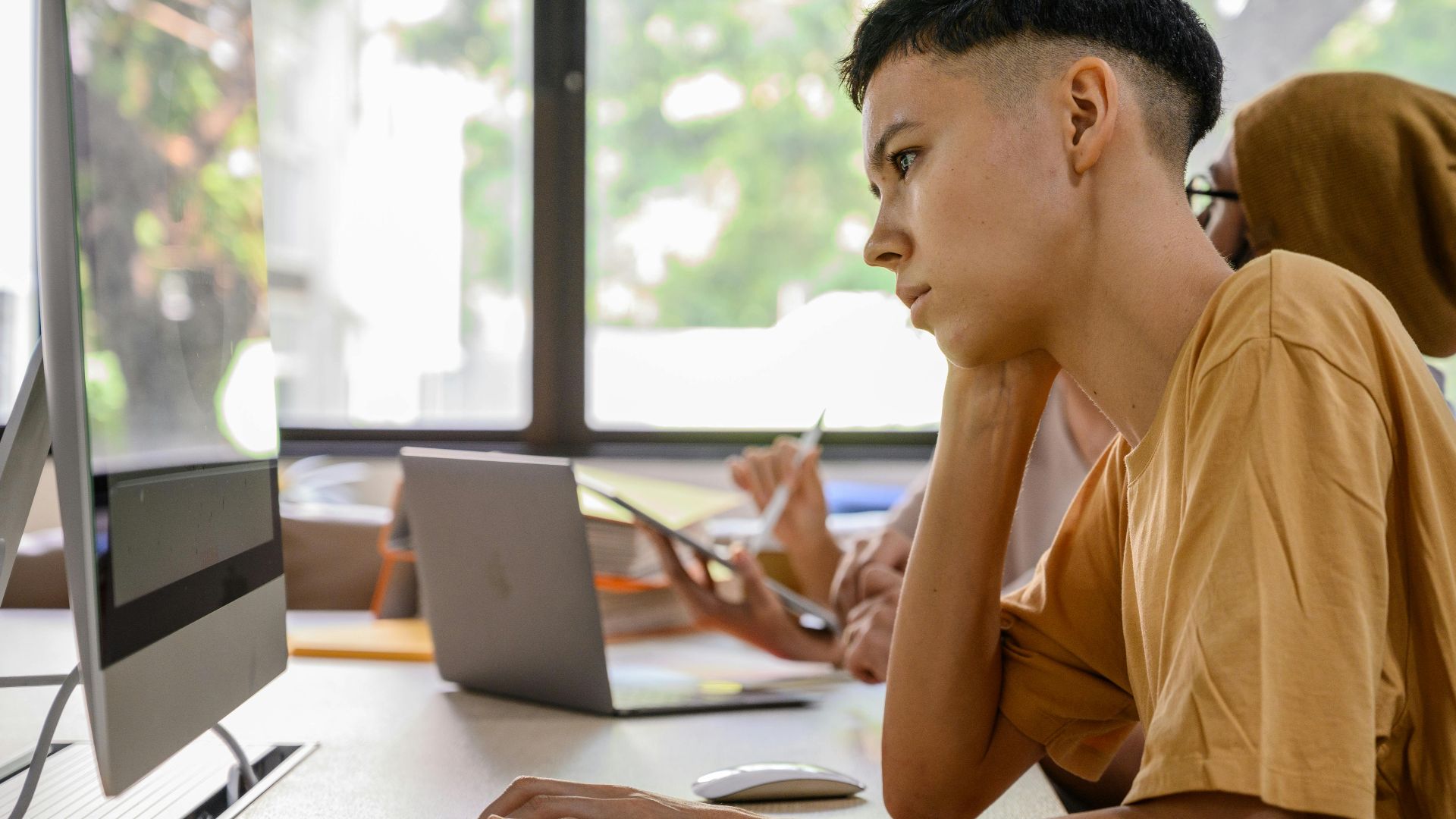 Young adults working intently at computers in an office setting.