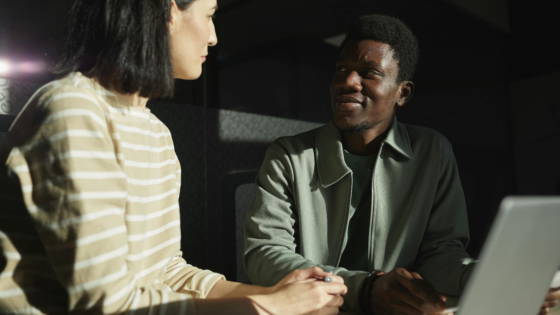 Two colleagues engaged in a thoughtful discussion, highlighting diversity in a modern office setting.