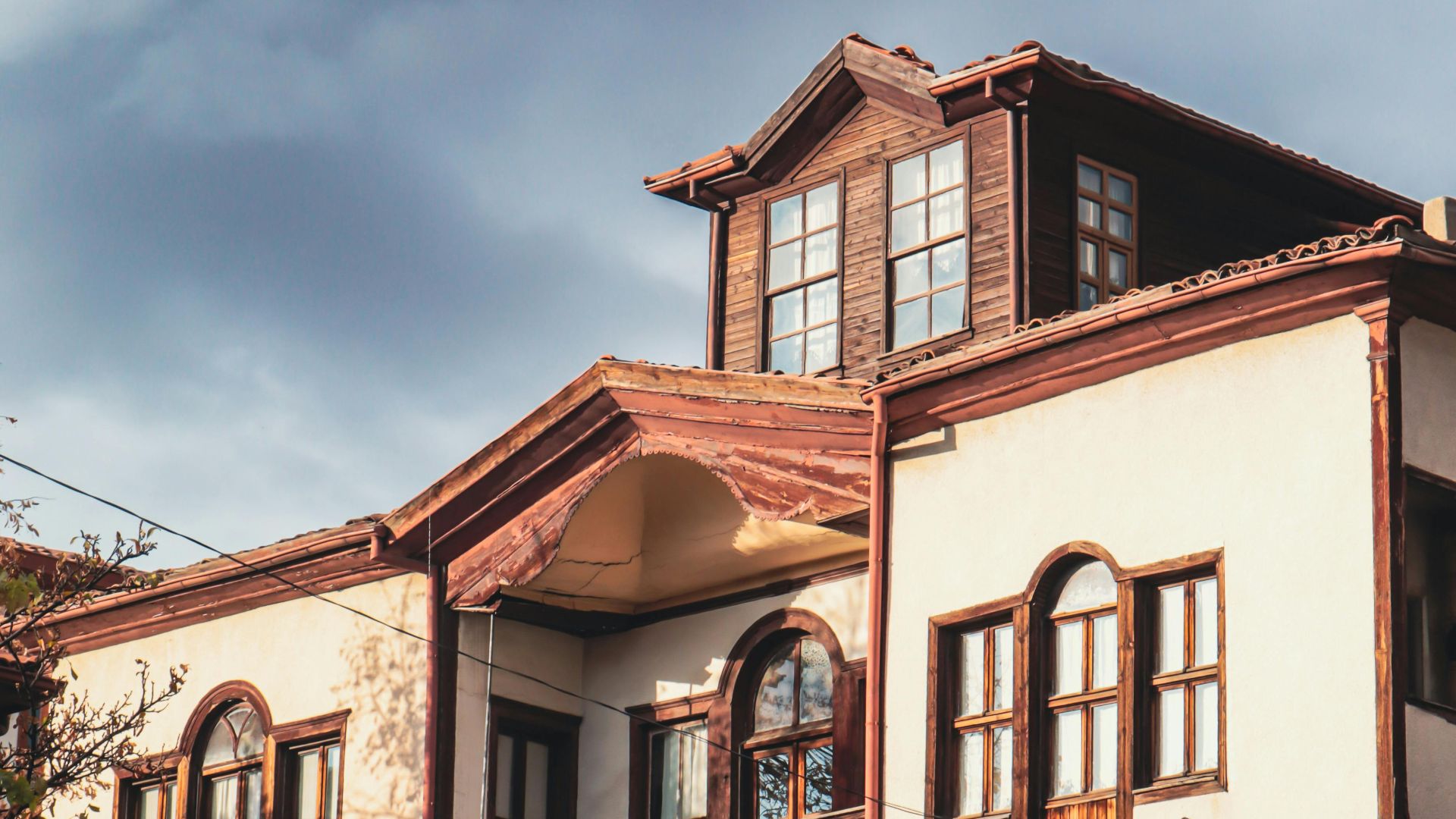 A vintage house with wooden accents captured under a cloudy sky, showcasing rustic architecture.