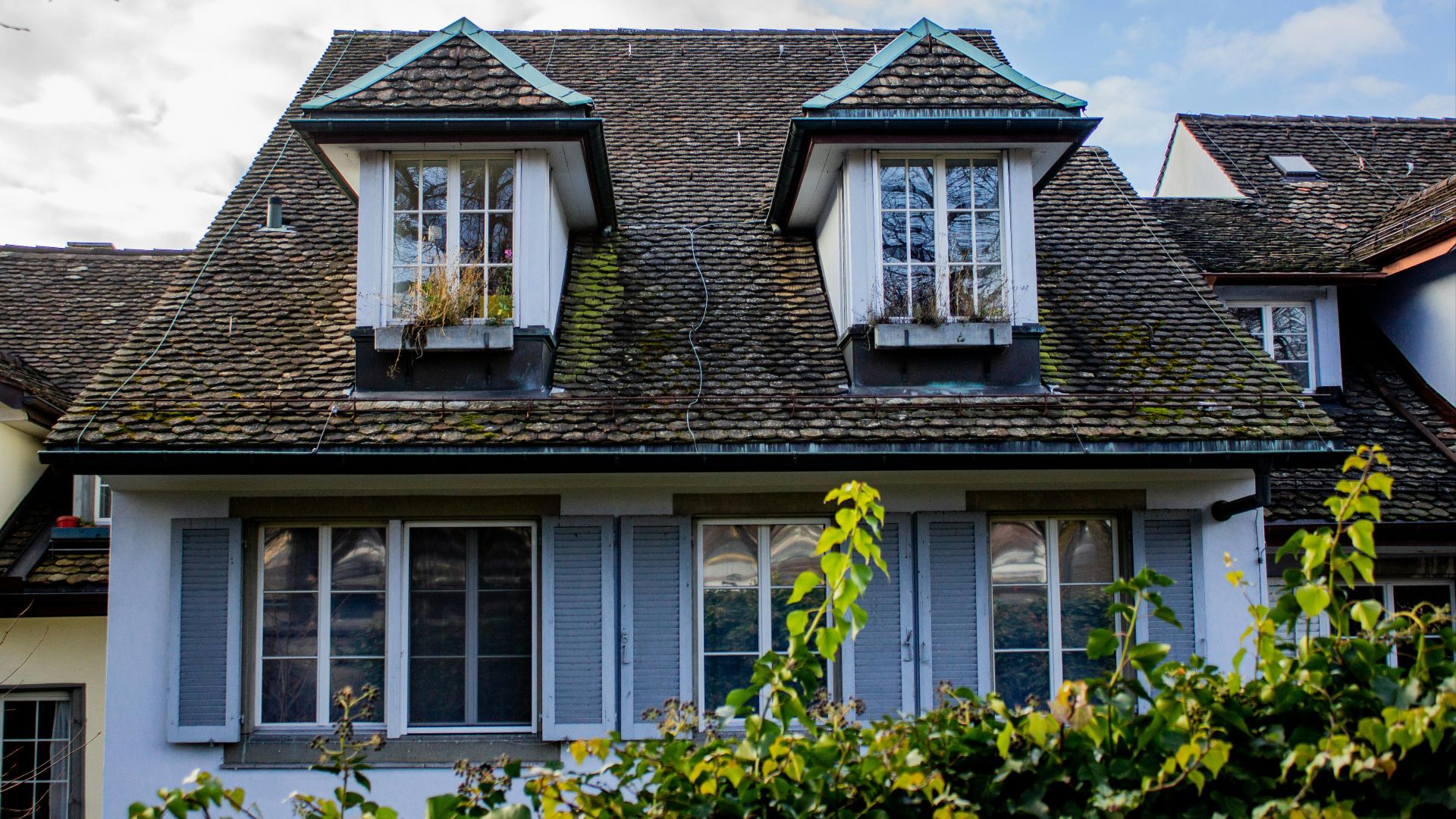 Rustic Swiss house in Zurich featuring traditional dormer windows and lush greenery.