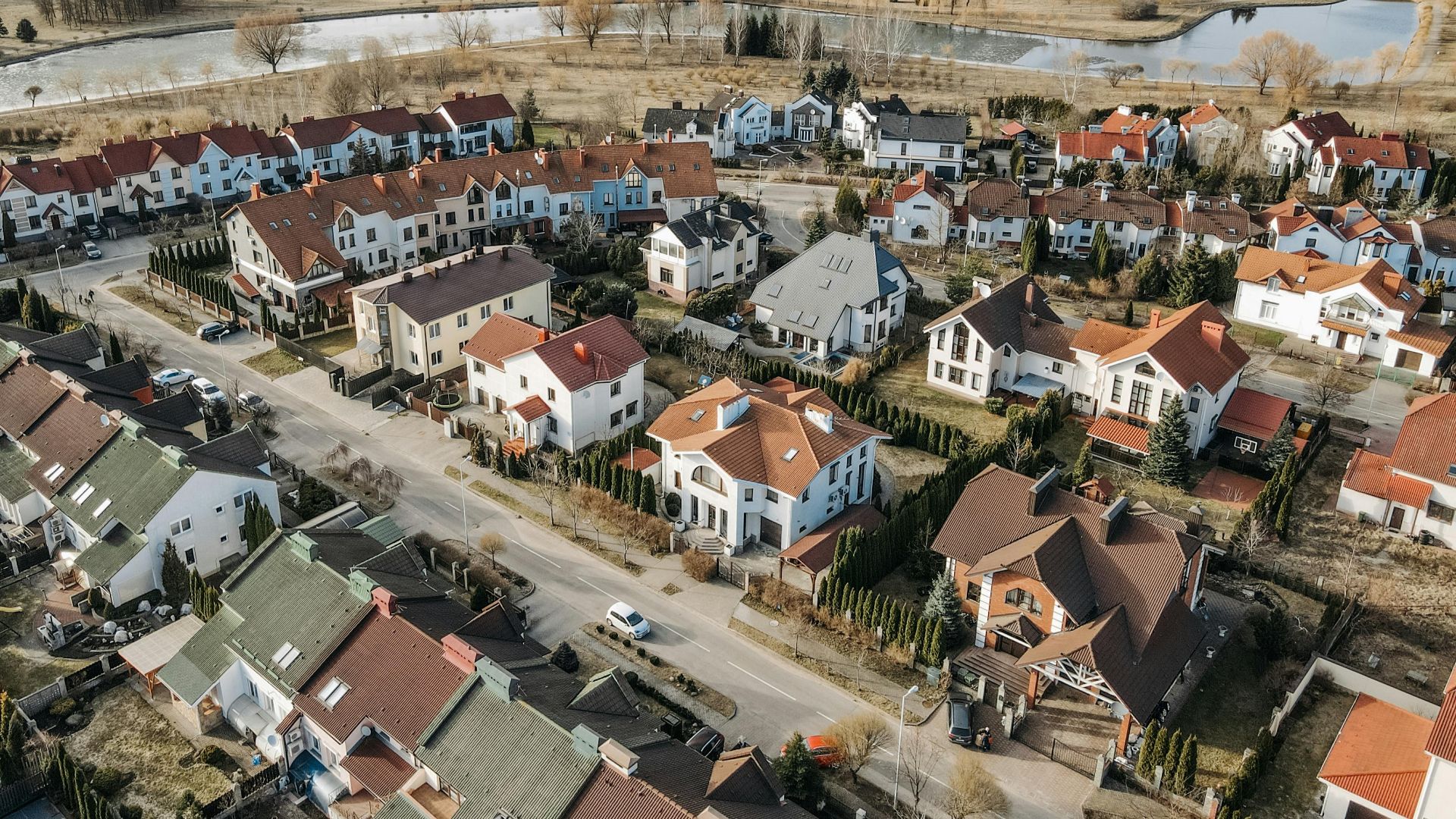 Aerial photography capturing a vibrant suburban neighborhood with distinct red-roofed houses and surrounding greenery.