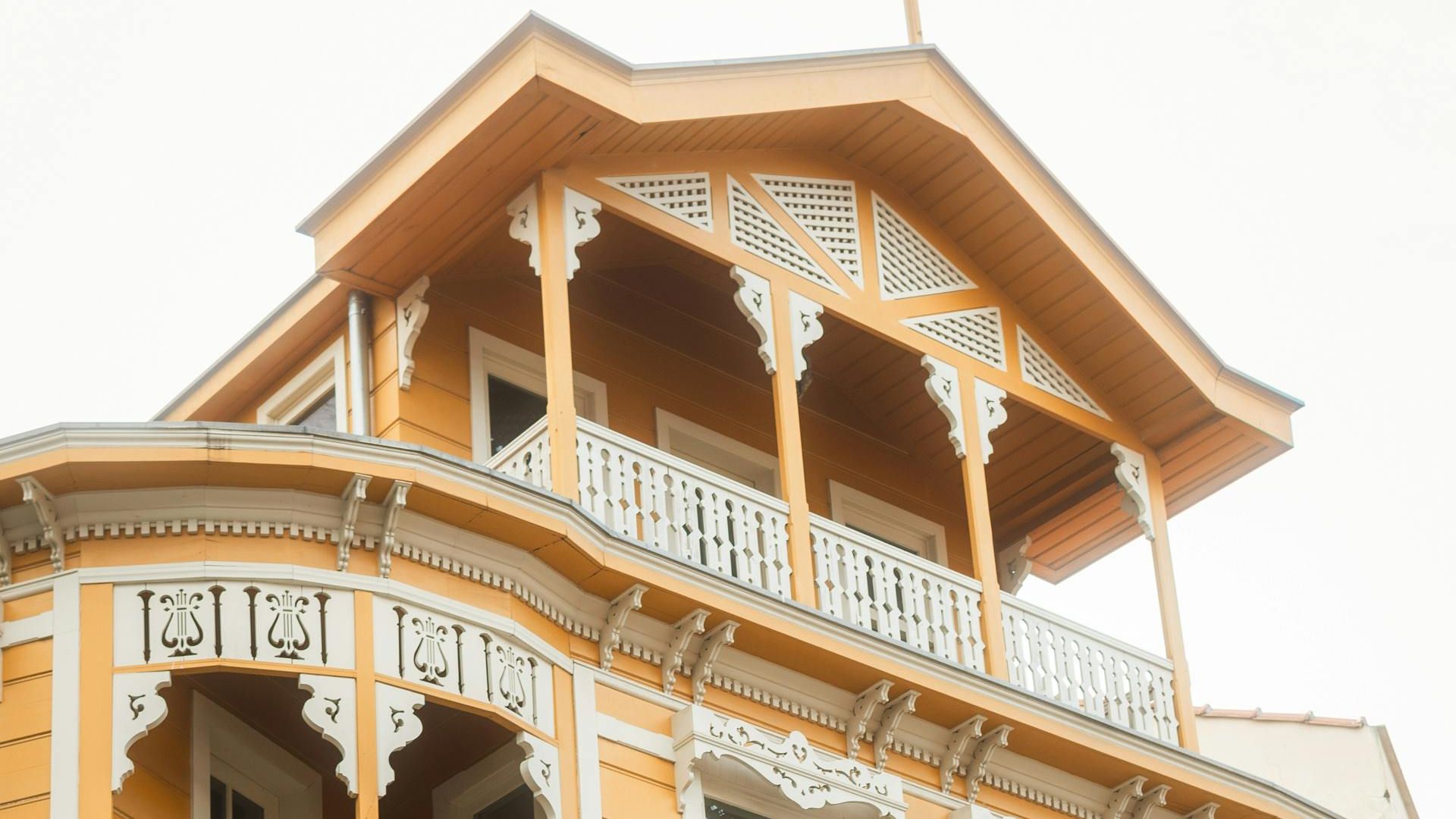 Elegant yellow Victorian house with detailed white trim and classic architecture captured in a low angle shot.
