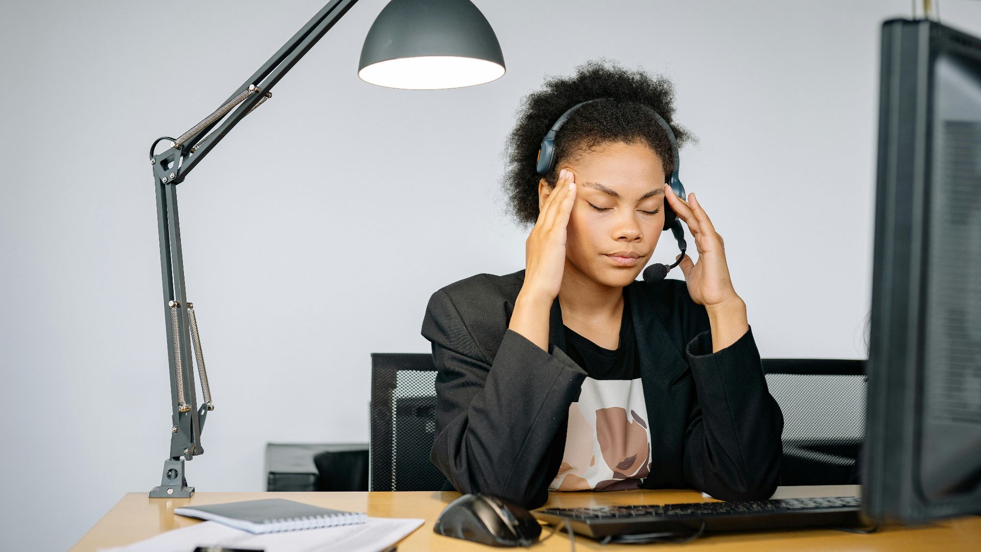 Exhausted call center agent with headset, tired from work, in an indoor office setting.