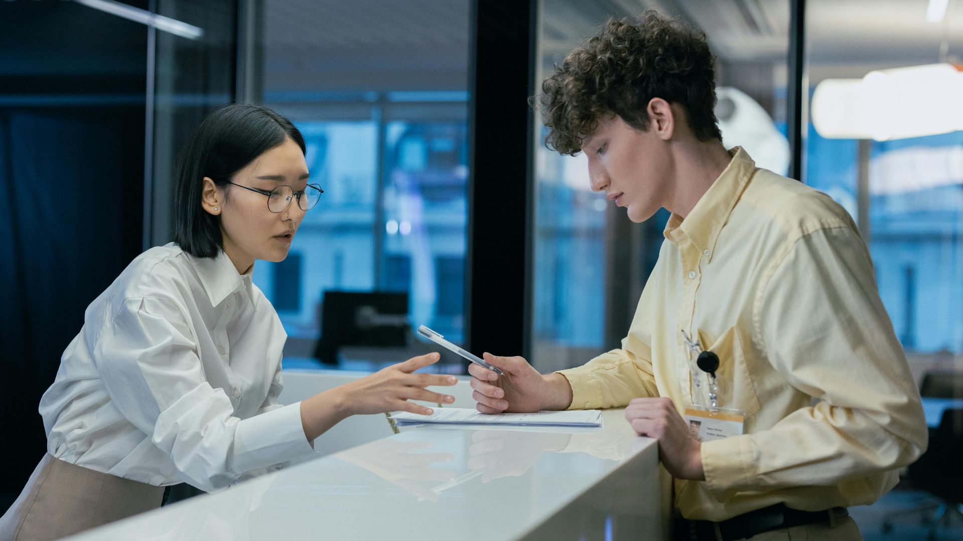 Two professionals discussing at a modern reception, highlighting teamwork and customer service.