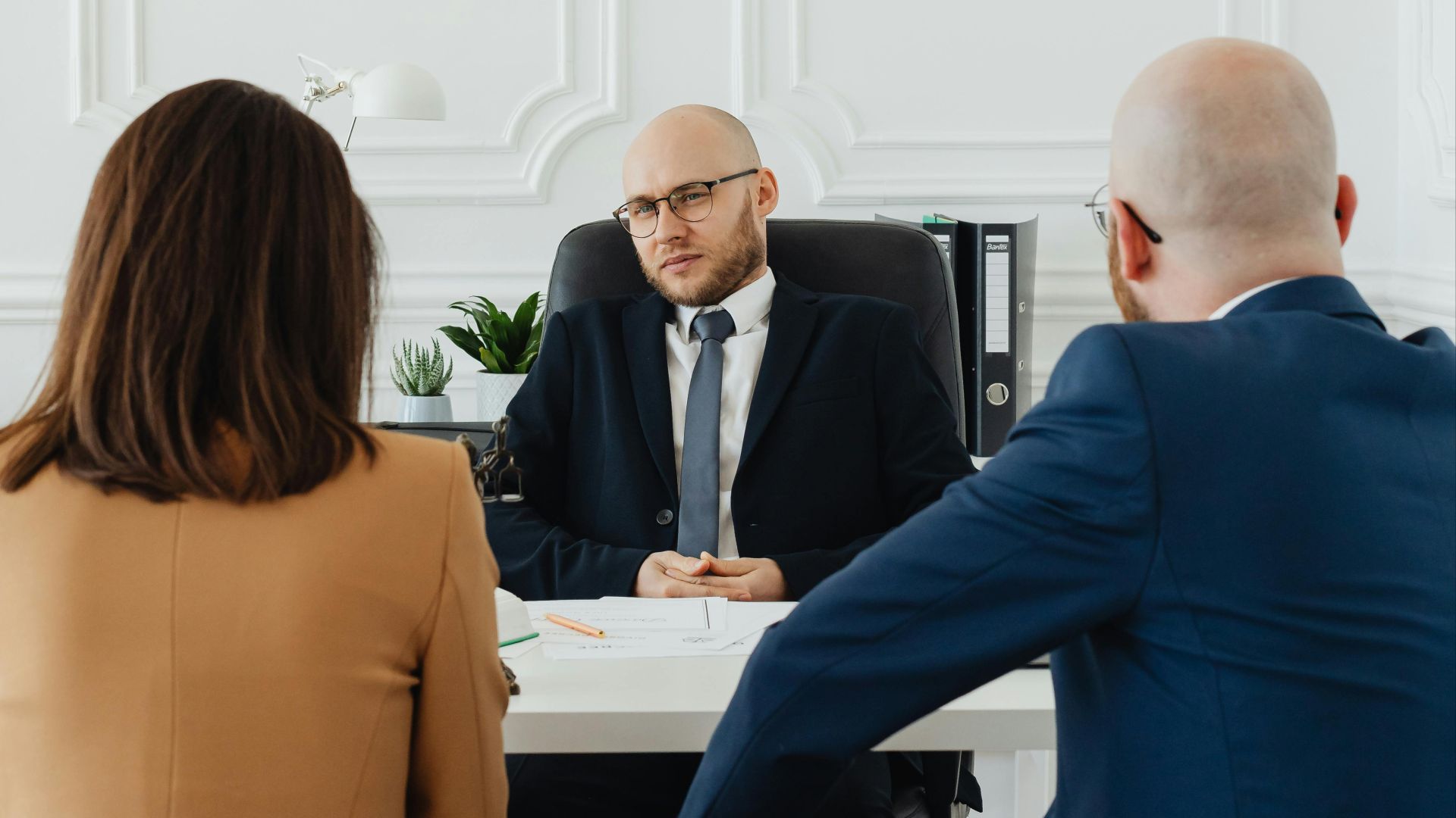 A lawyer consults a couple on divorce proceedings in an elegant office setting.