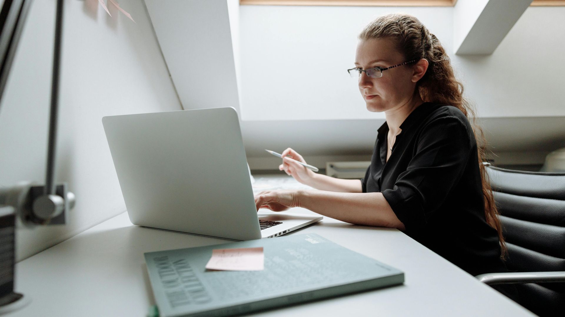 Focused woman working remotely on laptop in modern office setting