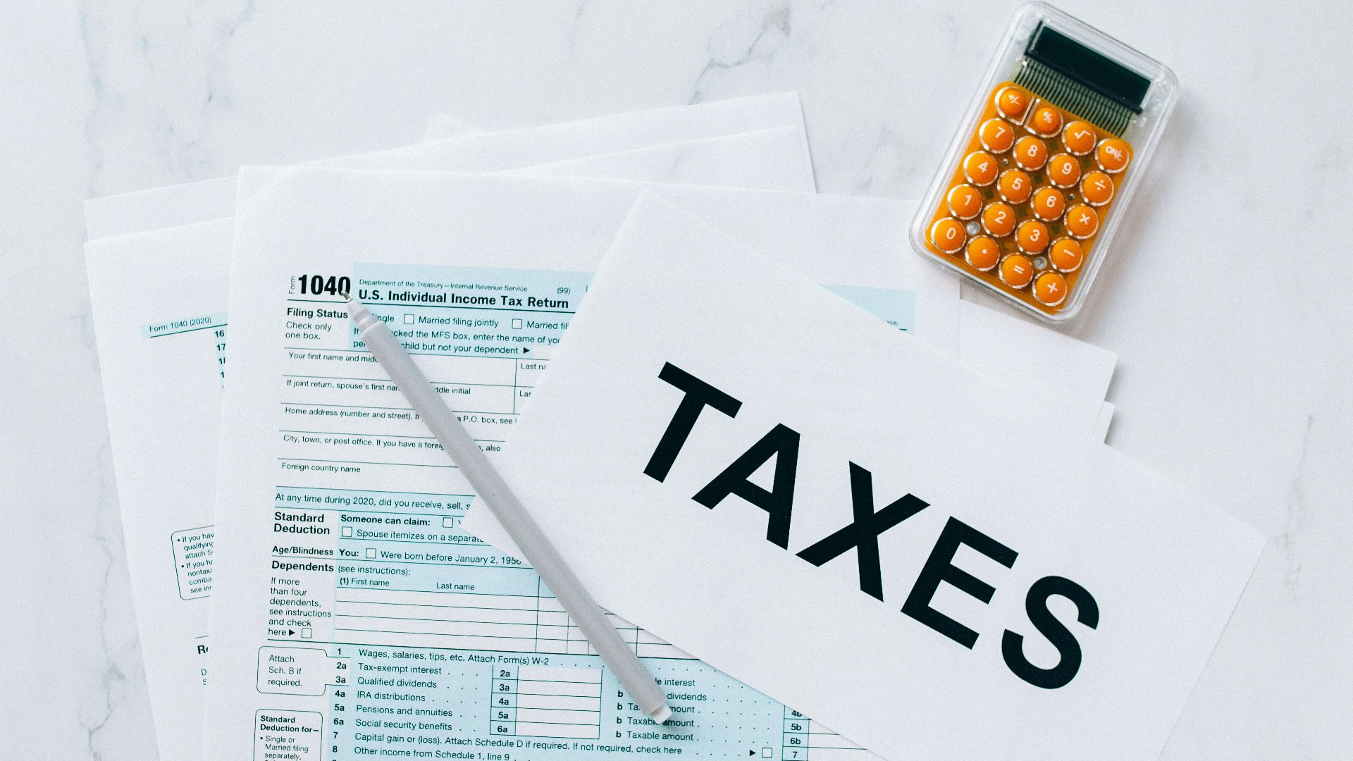 Top view of tax forms, a calculator, and pen for tax preparation.