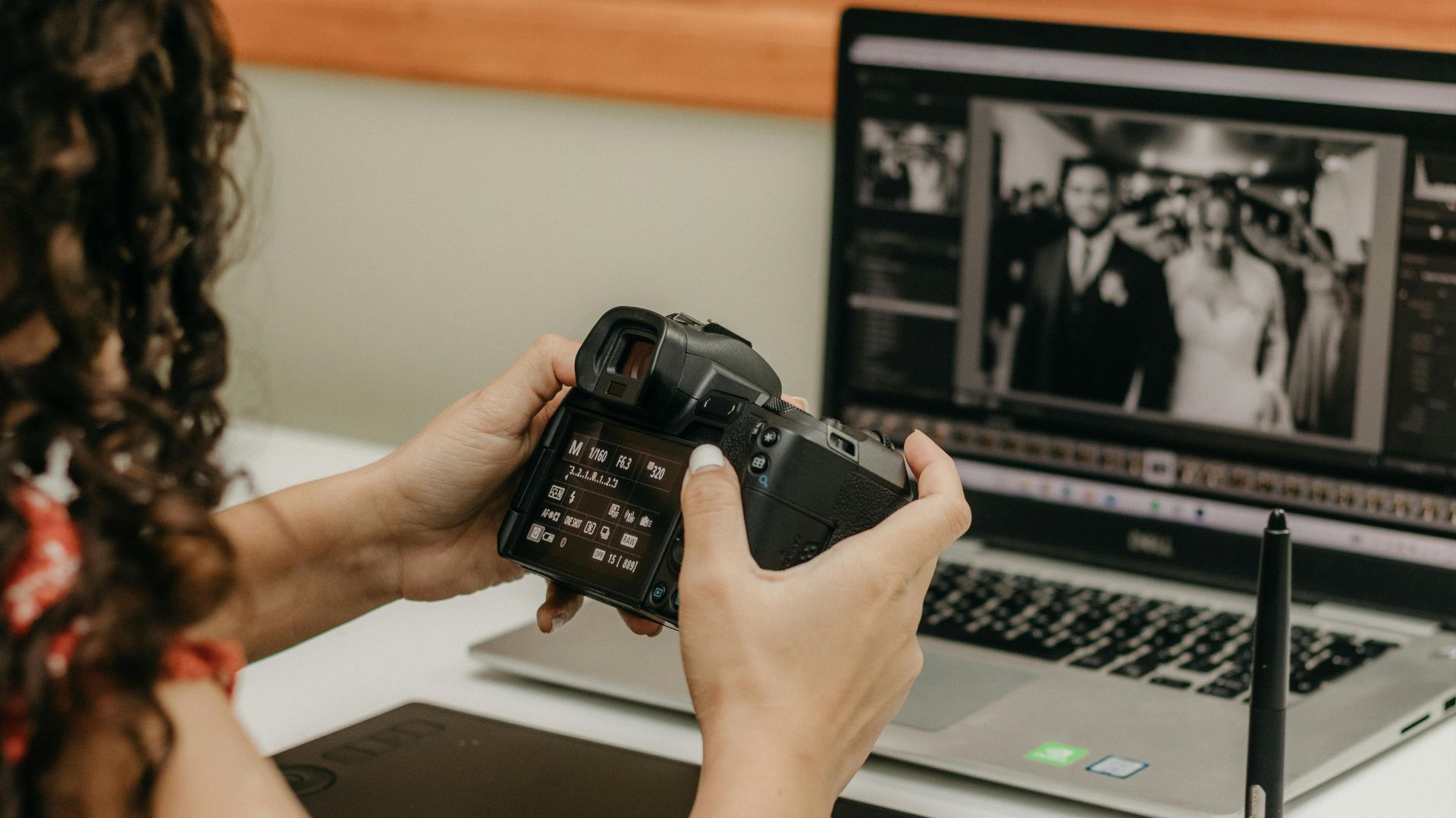 Photographer reviews camera settings while editing wedding photos on a laptop.