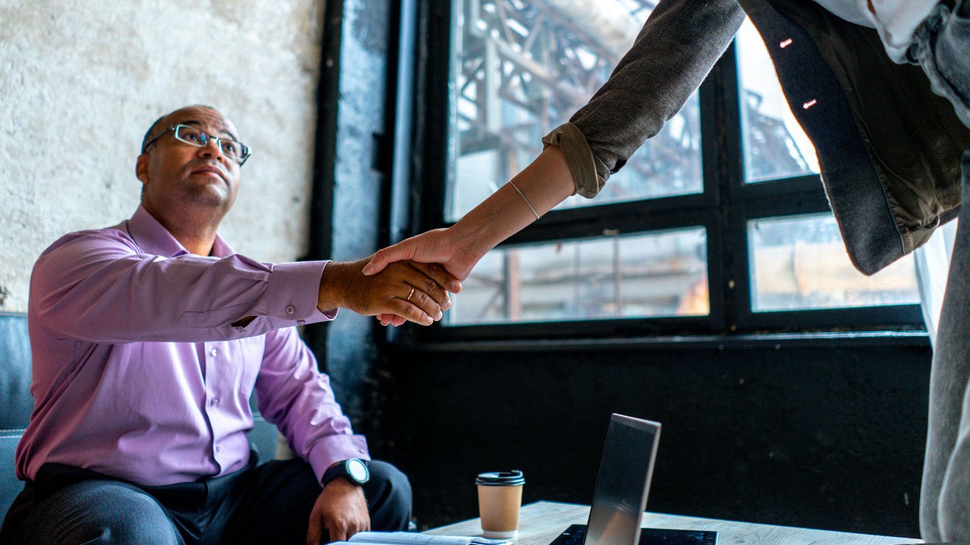 Professional handshake in an urban office setting, symbolizing agreement and networking.