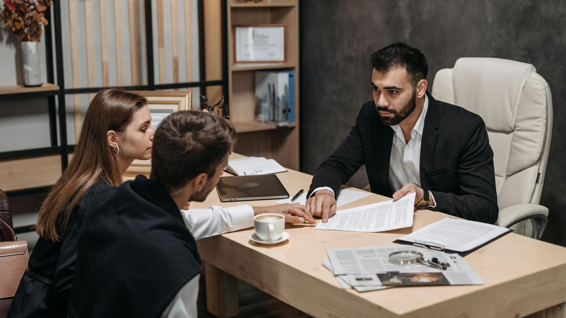 Lawyer discussing legal documents with clients at office desk.