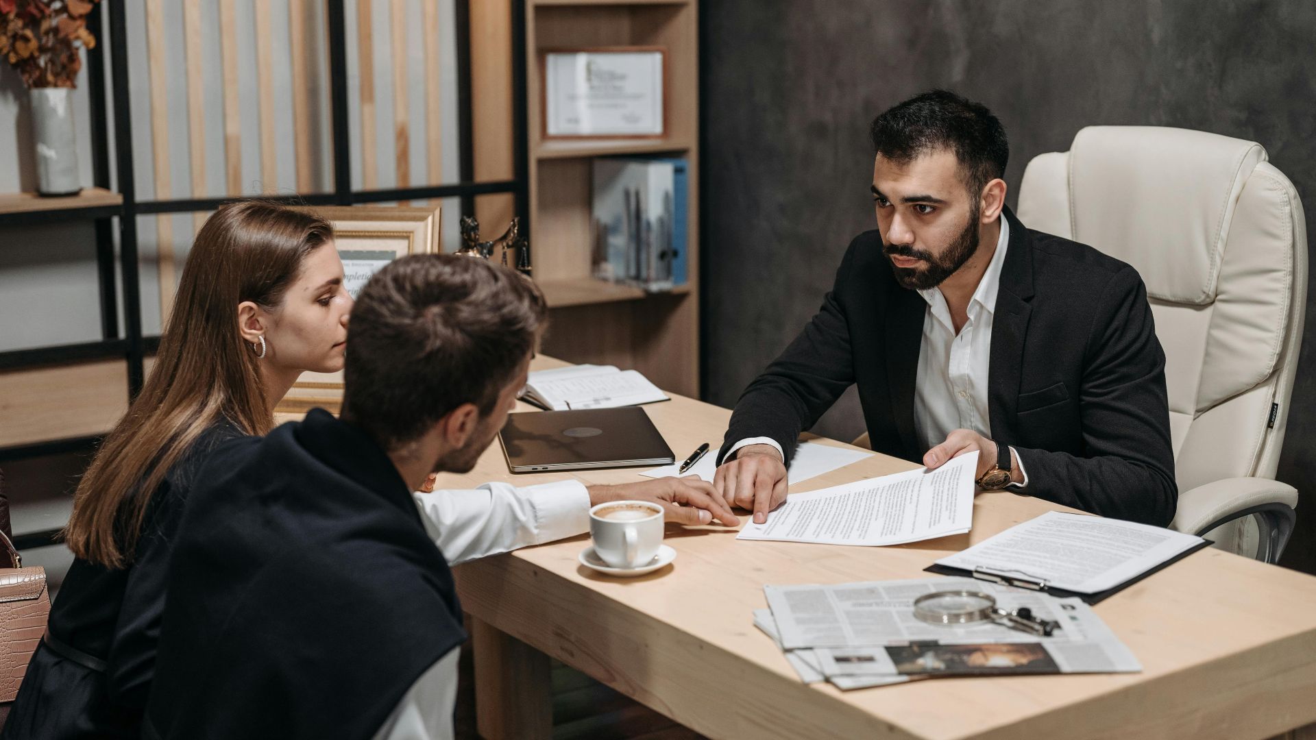 Lawyer discussing legal documents with clients at office desk.
