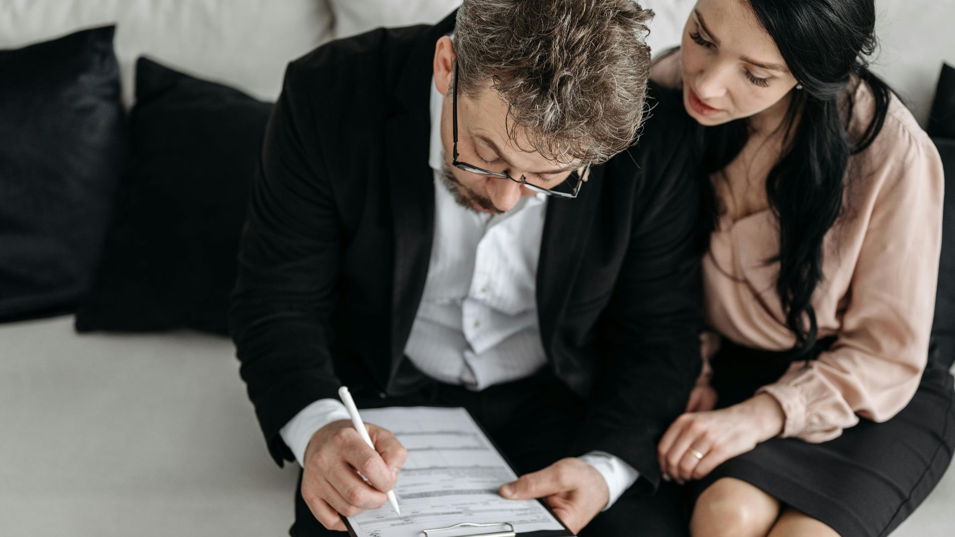 An adult couple sitting together reviewing documents in a modern indoor setting.