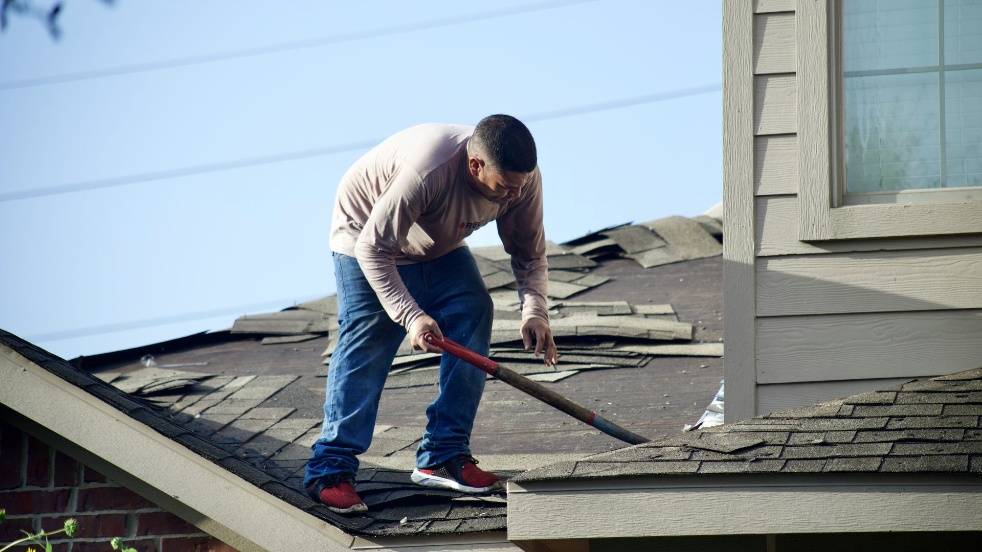 a man with a hammer on top of a roof