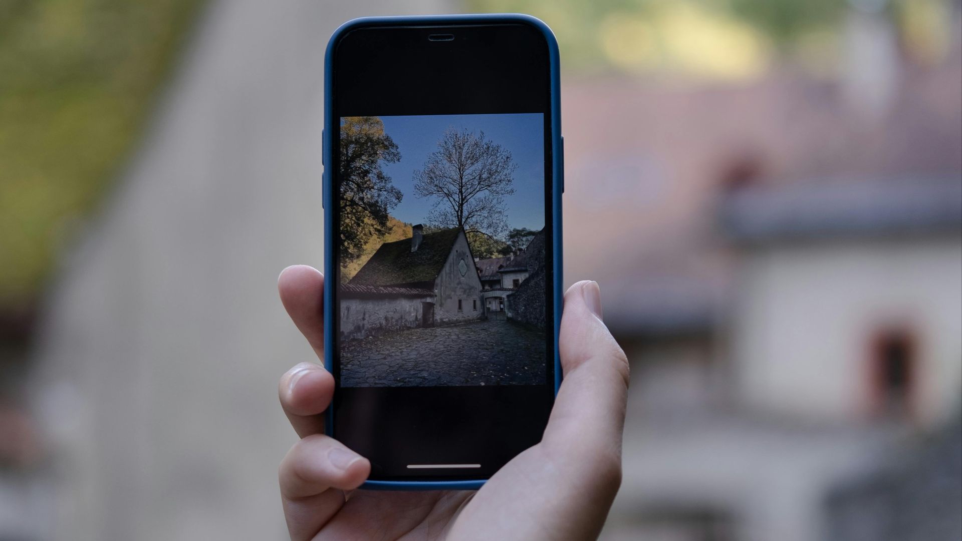 A hand holds a smartphone capturing a historic building outdoors.