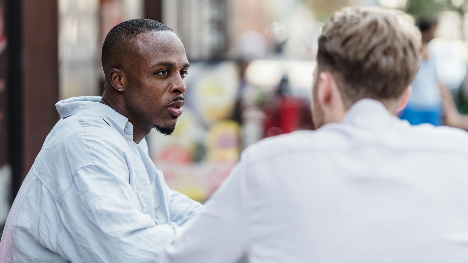 Two men having a conversation in an outdoor setting on a sunny day.
