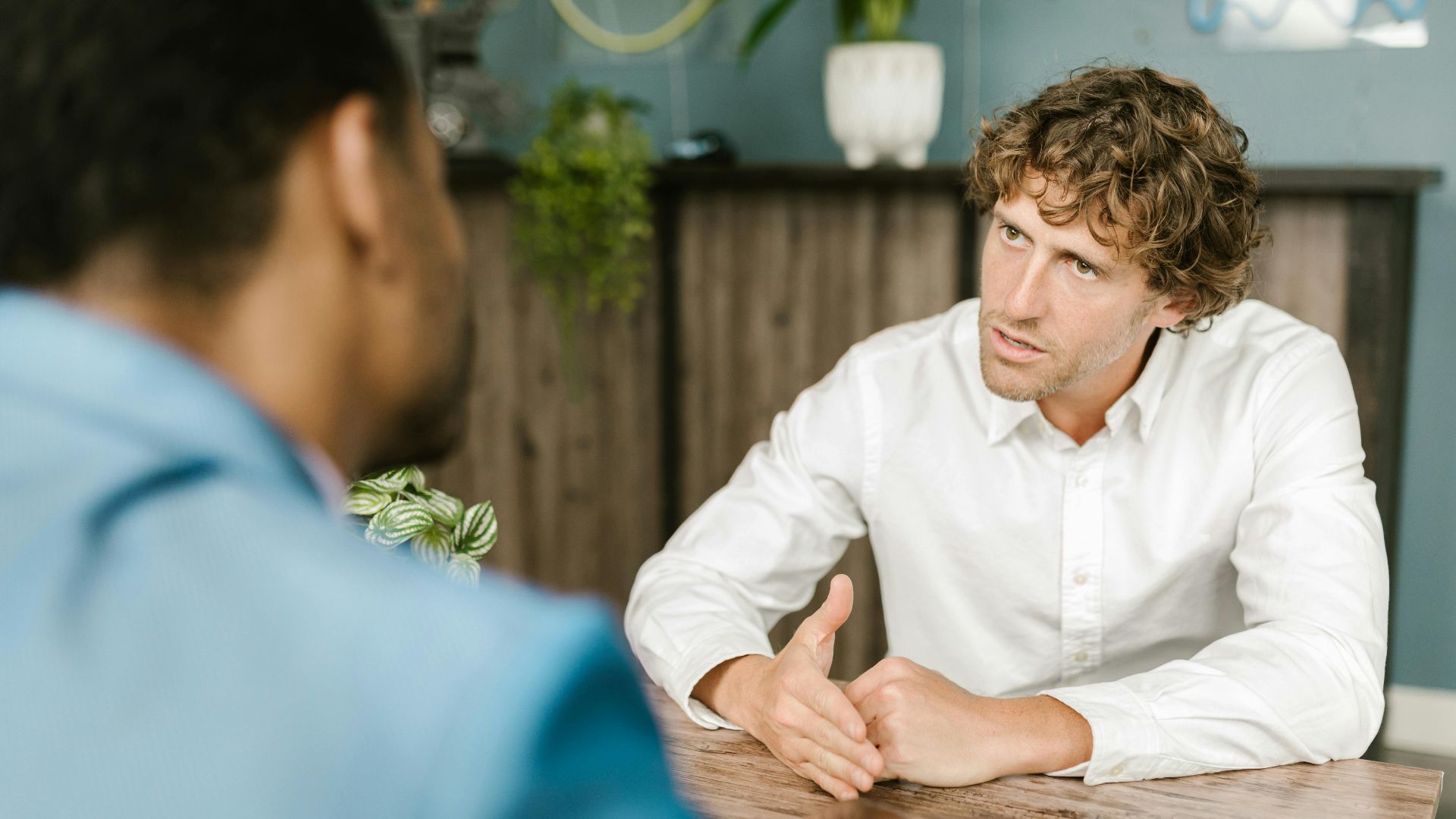 Men in office attire having a focused conversation at a wooden table.