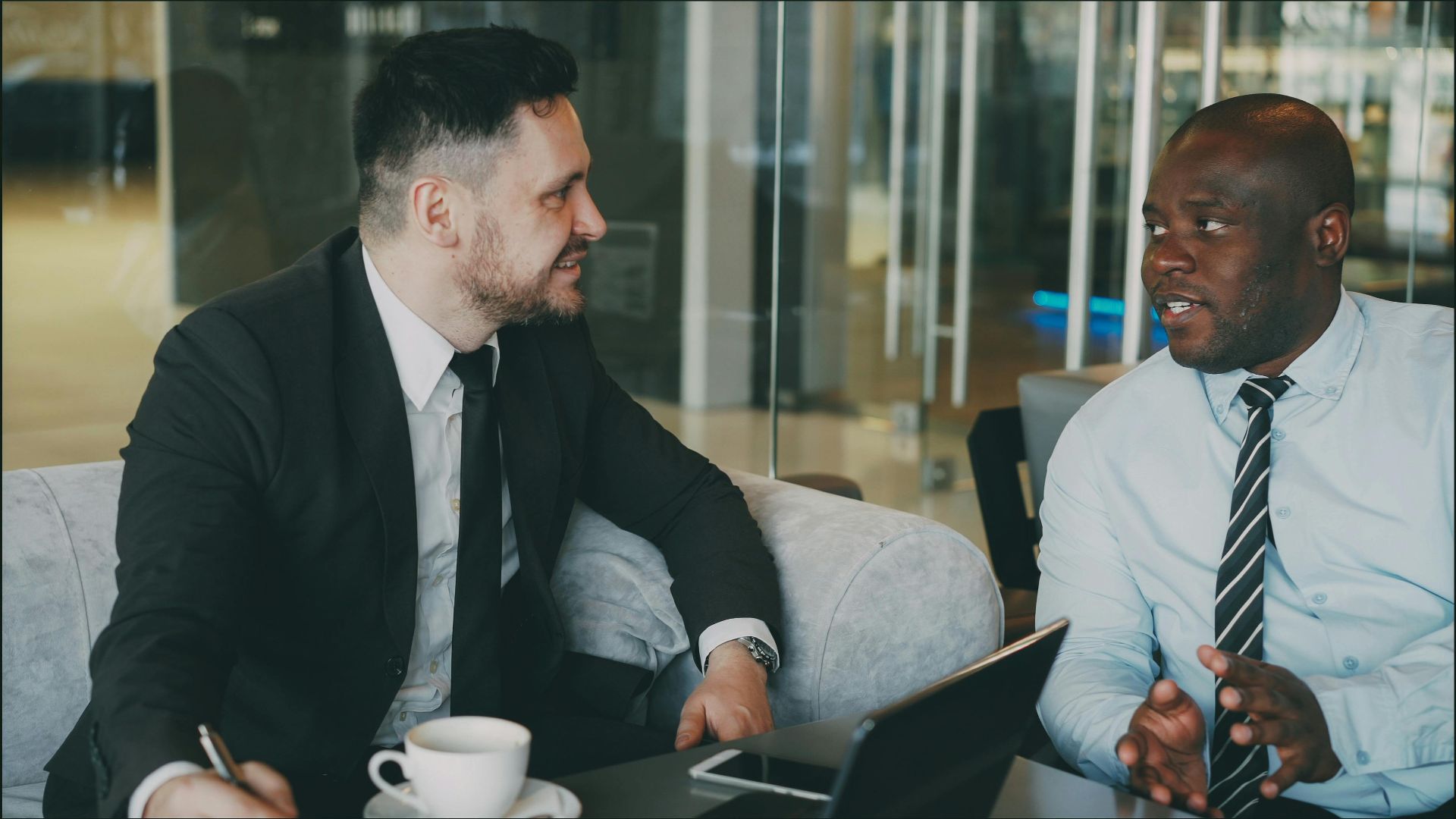 Two businessmen having a discussion in a modern cafe setting.