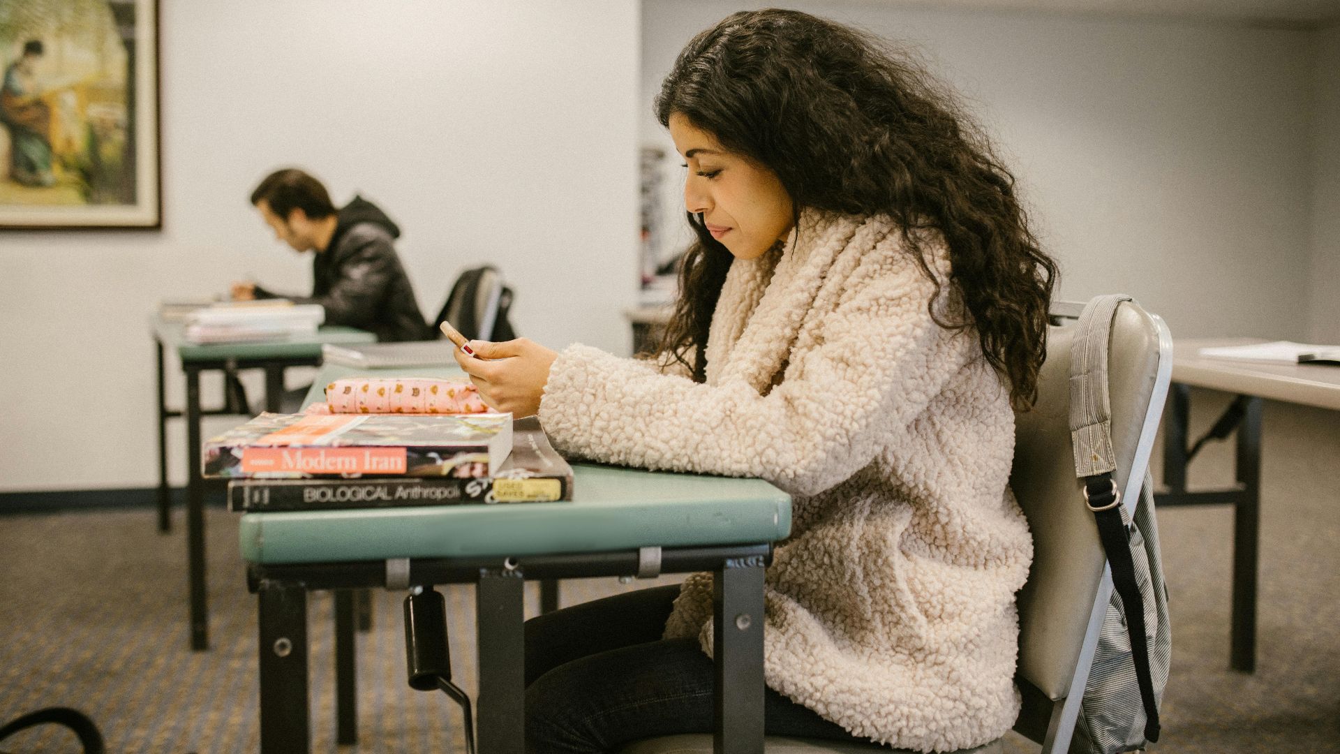 Female college student focusing on study materials in a classroom setting.