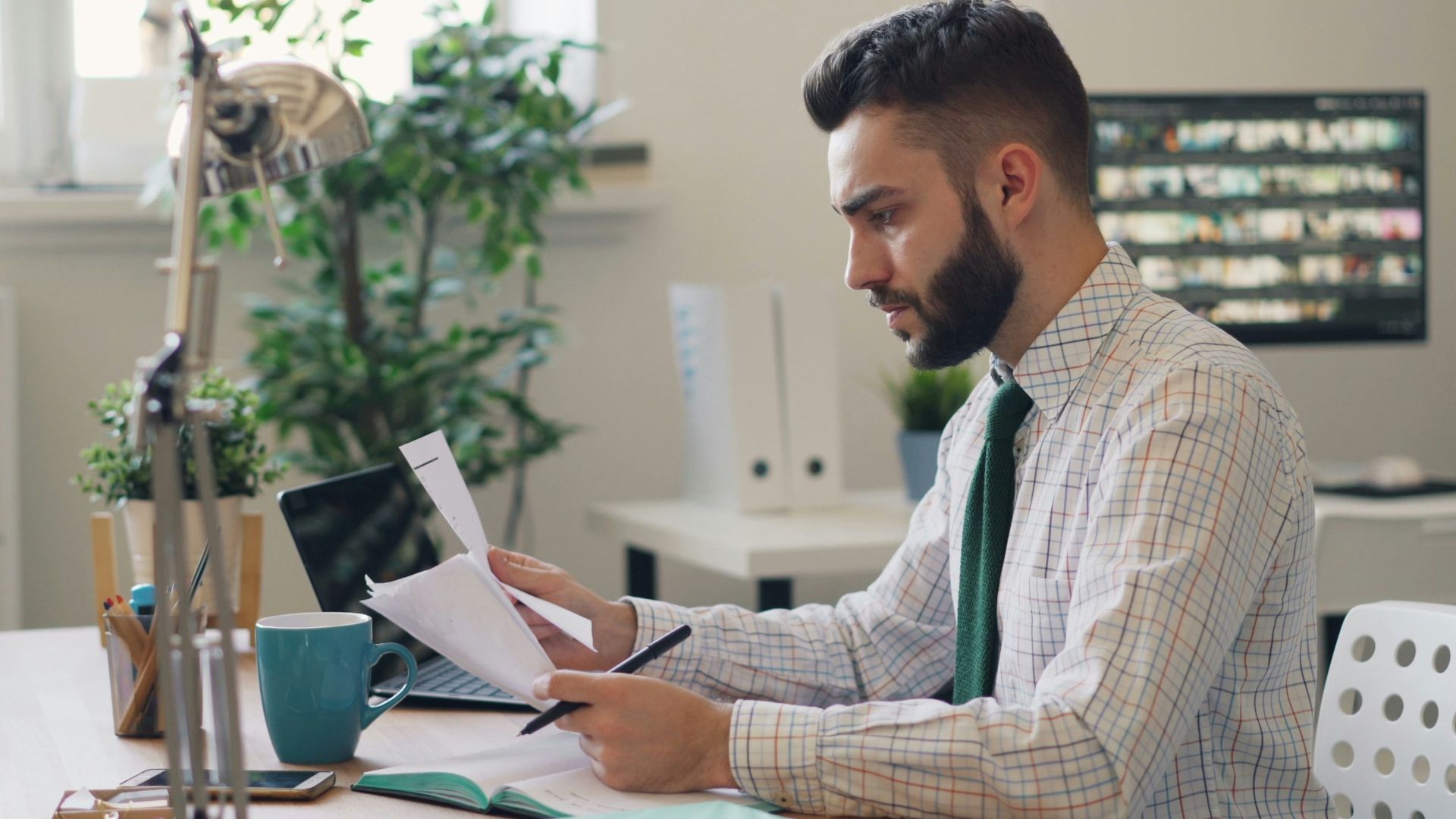 a man sitting at a desk with a laptop and papers