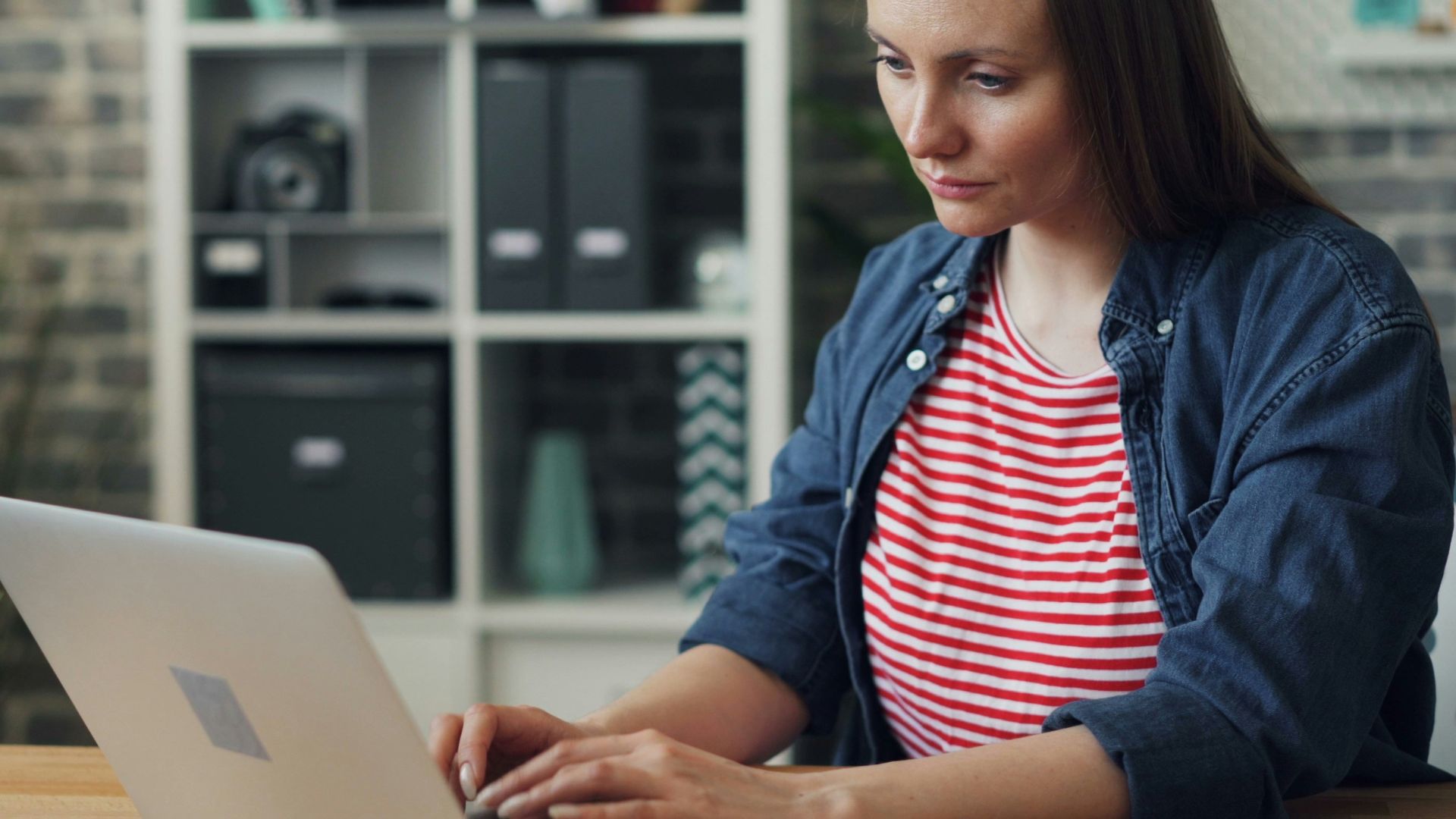 a woman sitting at a table using a laptop computer
