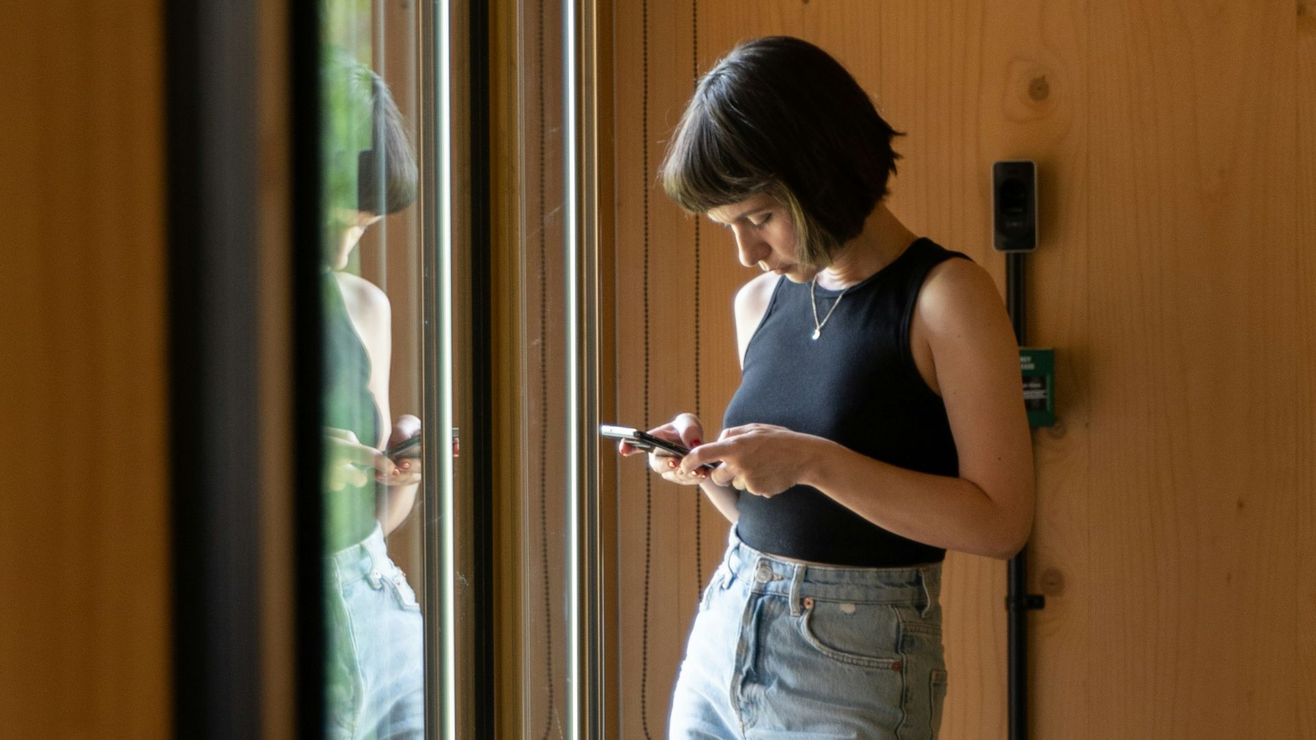 a woman standing in front of a door looking at her cell phone