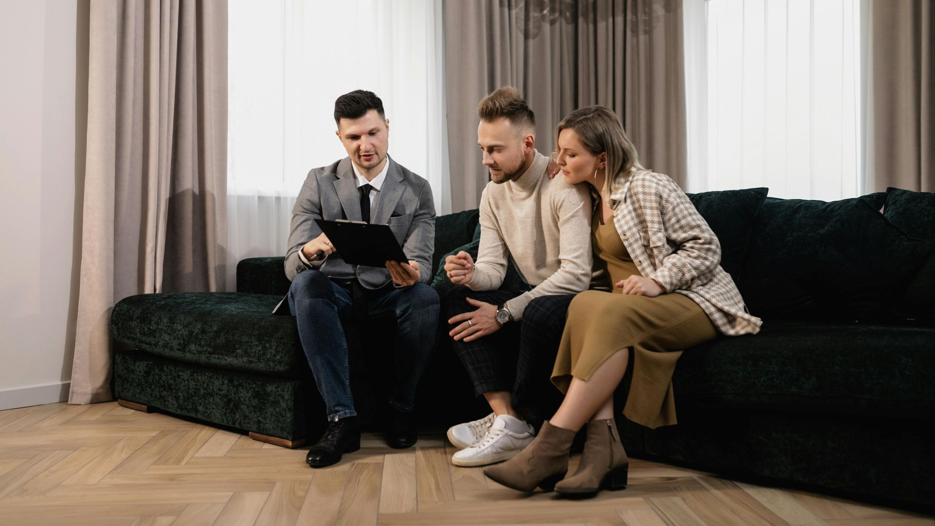 A real estate agent shows a property listing to a couple in a modern living room.