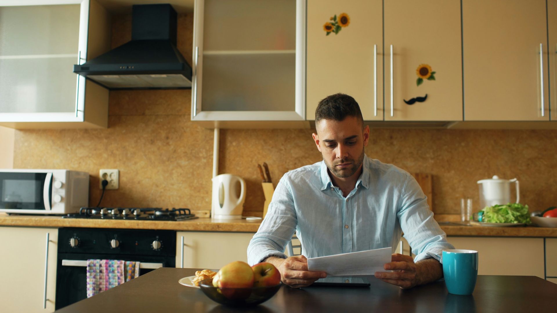 Man reading document at kitchen table with coffee