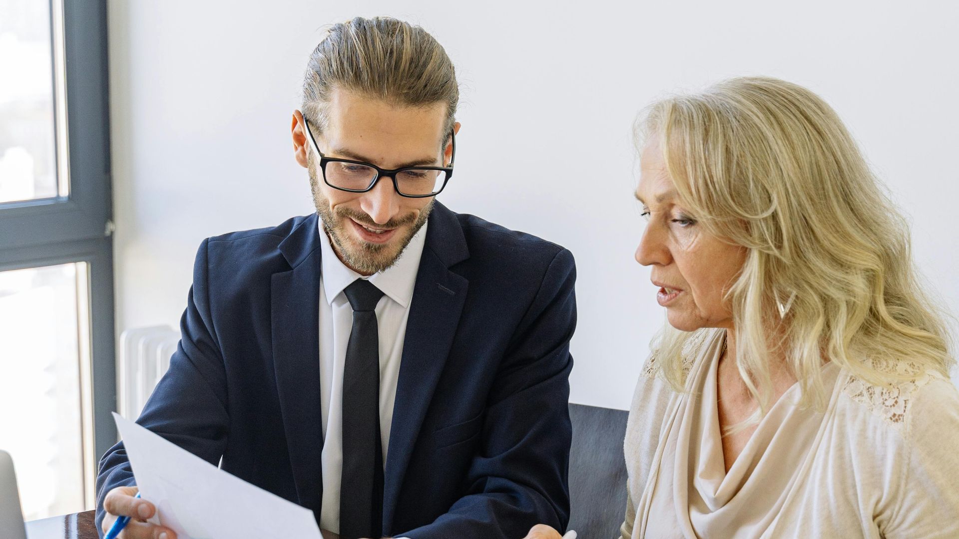 Two business professionals reviewing financial documents and graphs during a meeting.