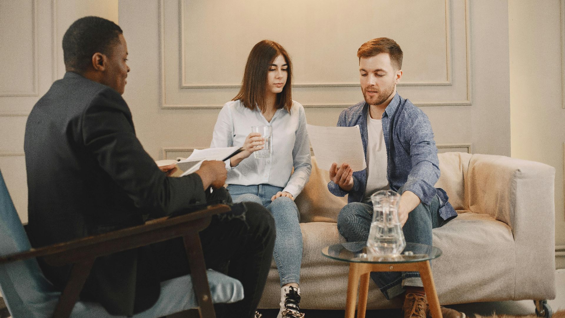 Therapist counseling couple with documents in contemporary office setting.