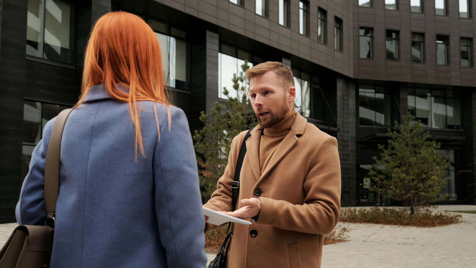 Two business professionals in conversation outside an urban office building.