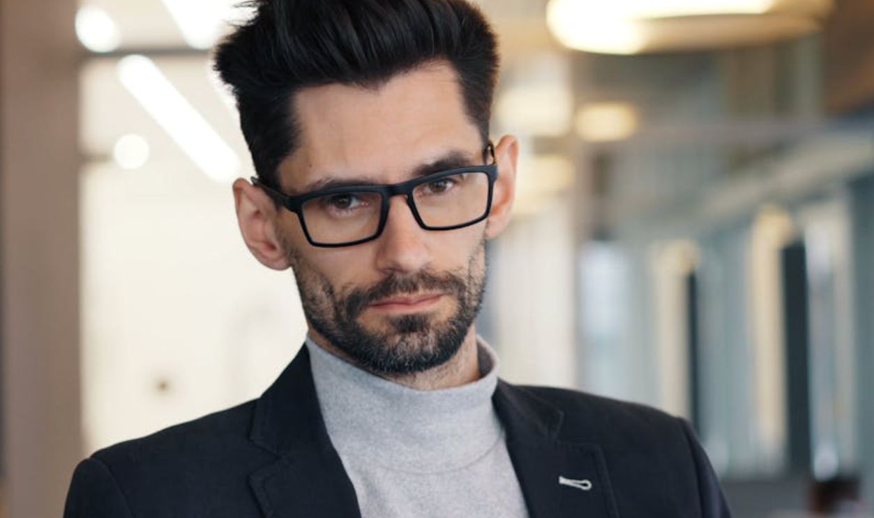 A man in glasses and a suit standing in an office