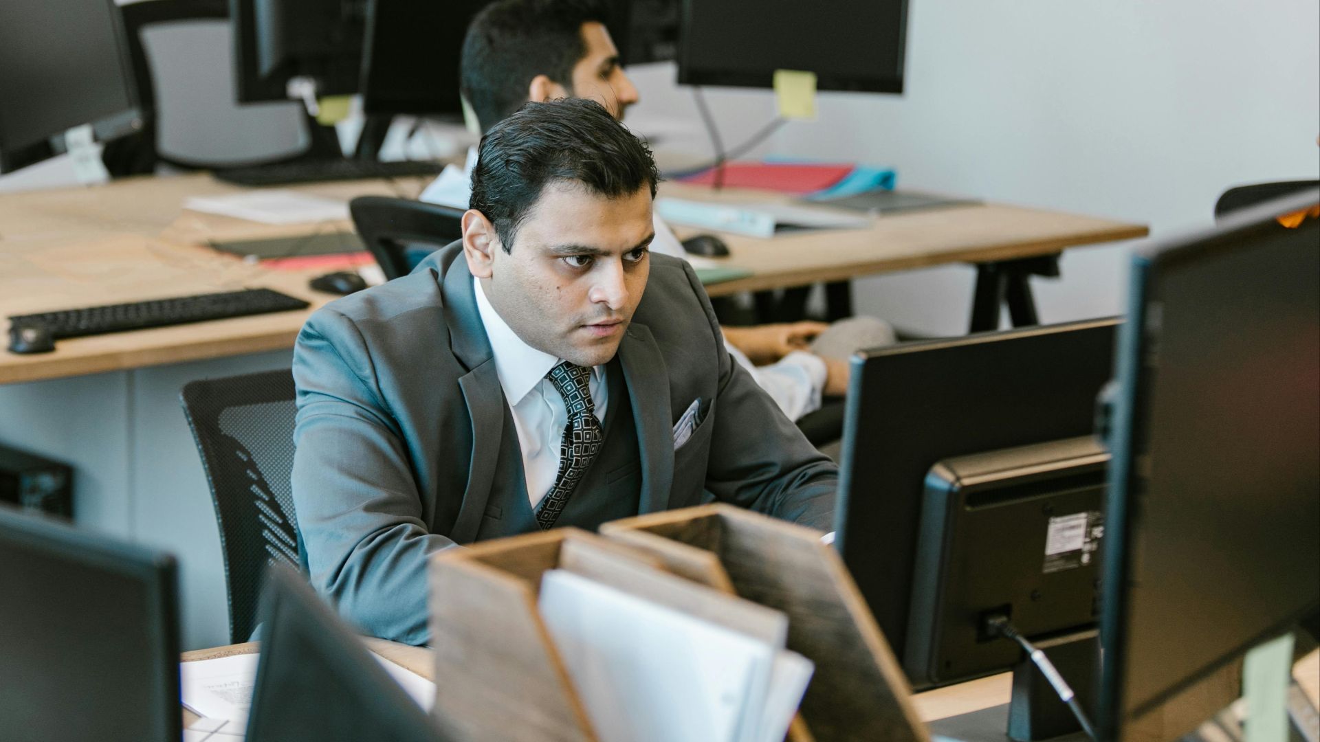 A dedicated businessman in a suit concentrating on work at a modern office desk.