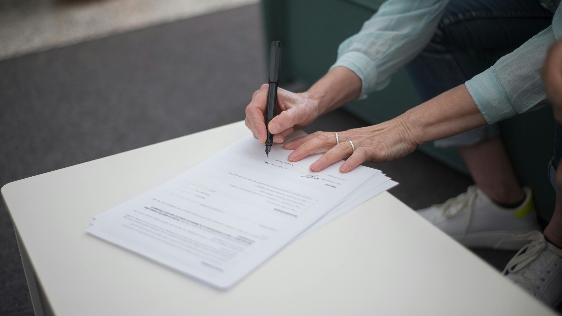 A person signing important legal documents on a table, emphasizing business and professionalism.
