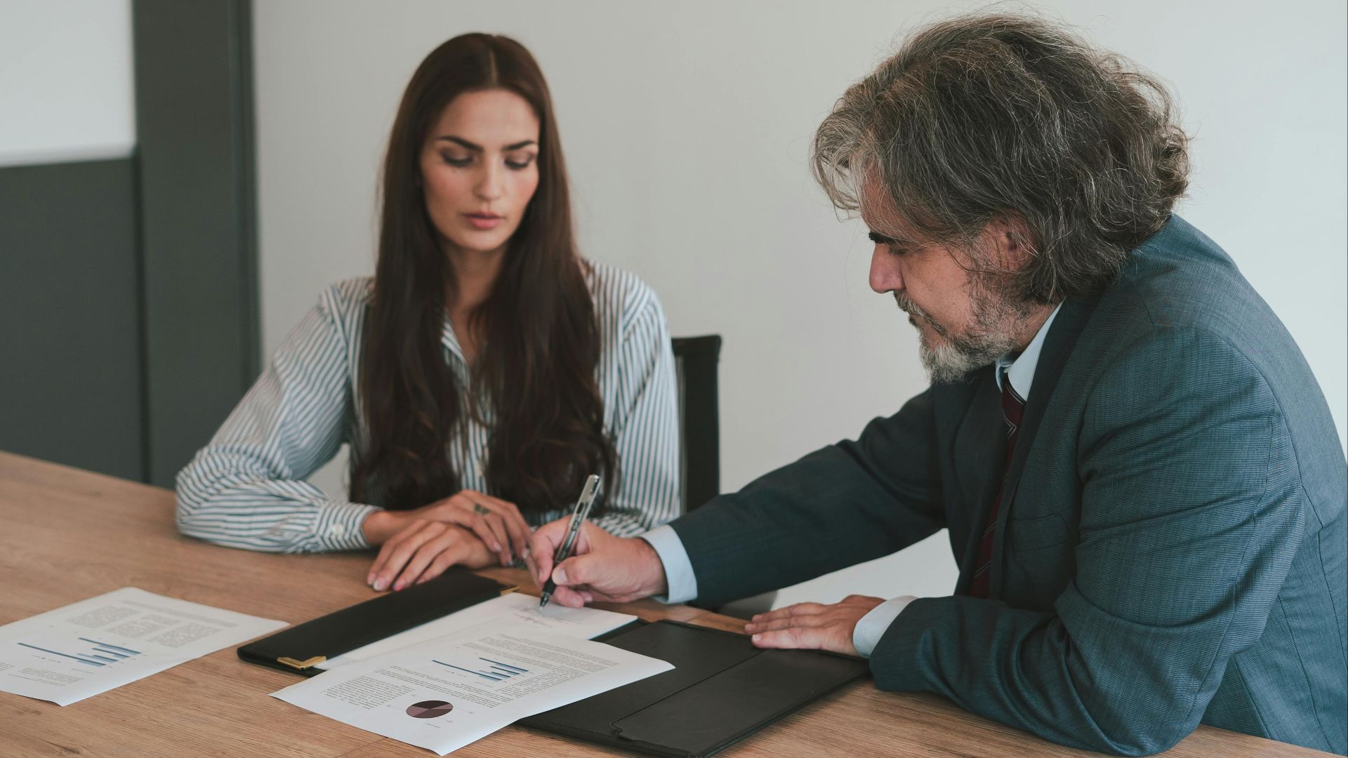 Professional business meeting with two colleagues reviewing documents at an office desk.