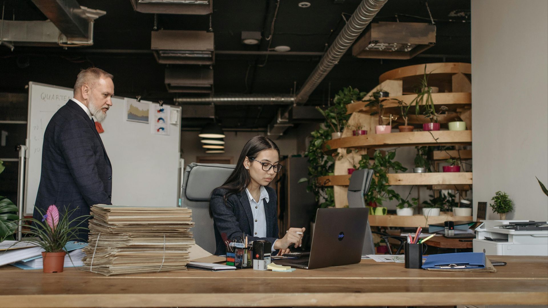 Business team in an office working together with modern equipment, plants, and documents.