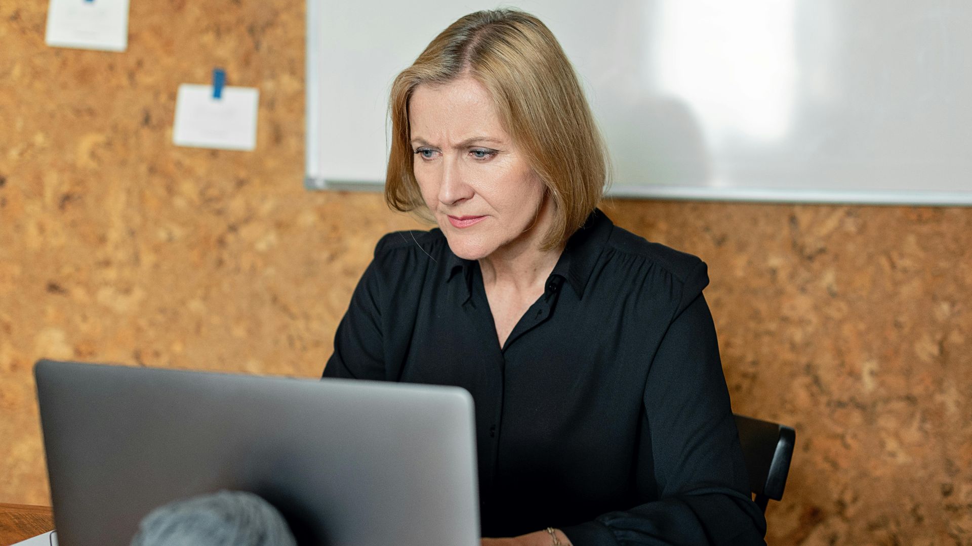Professional woman concentrating on work with laptop in an office environment.