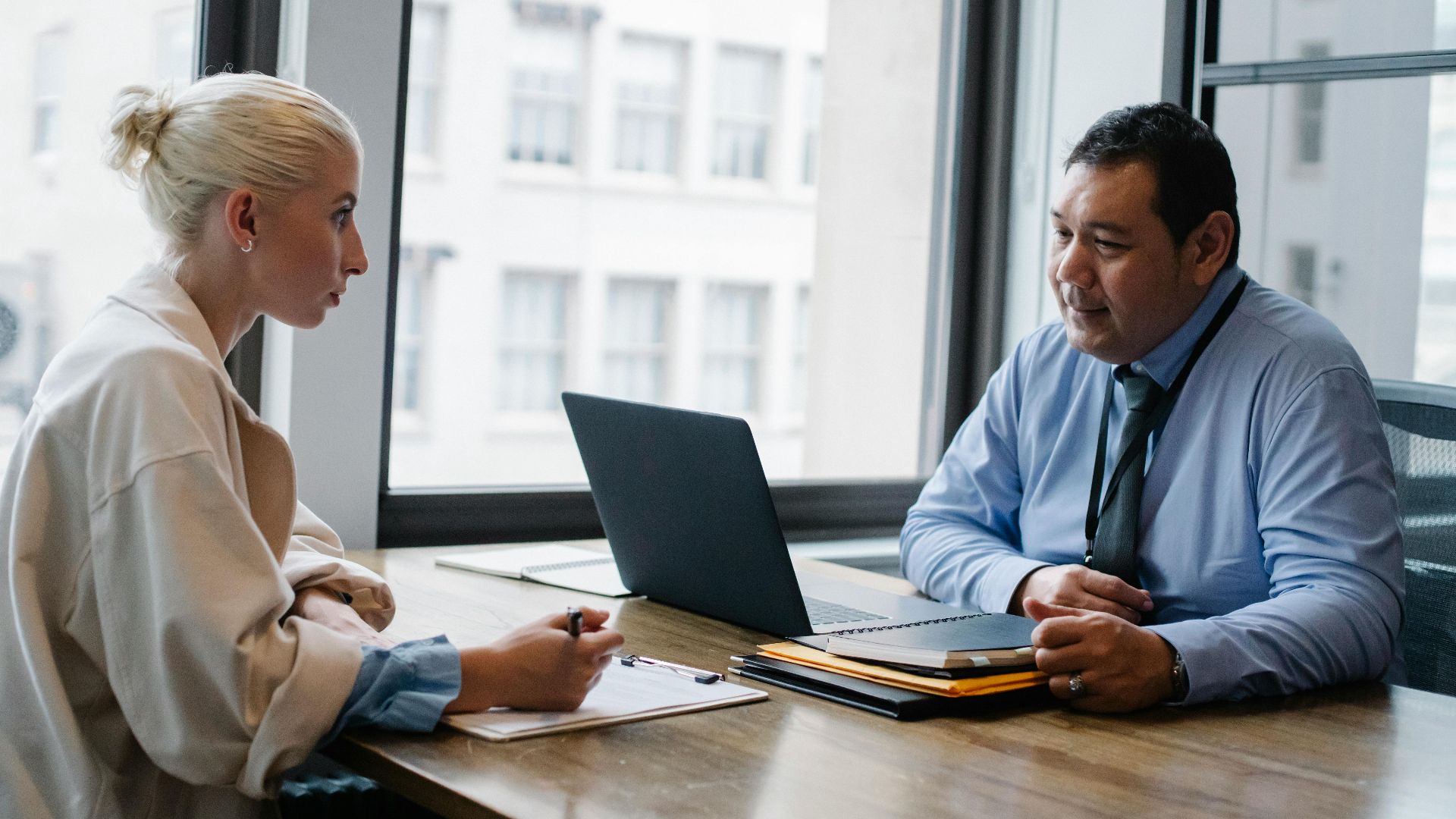 Ethnic boss asking question to female candidate filling information form on clipboard during hiring meeting