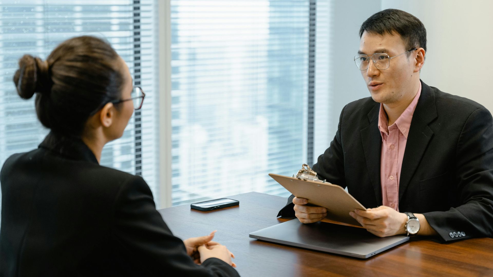 Two professionals discussing at an office table, indicating a formal meeting setting.