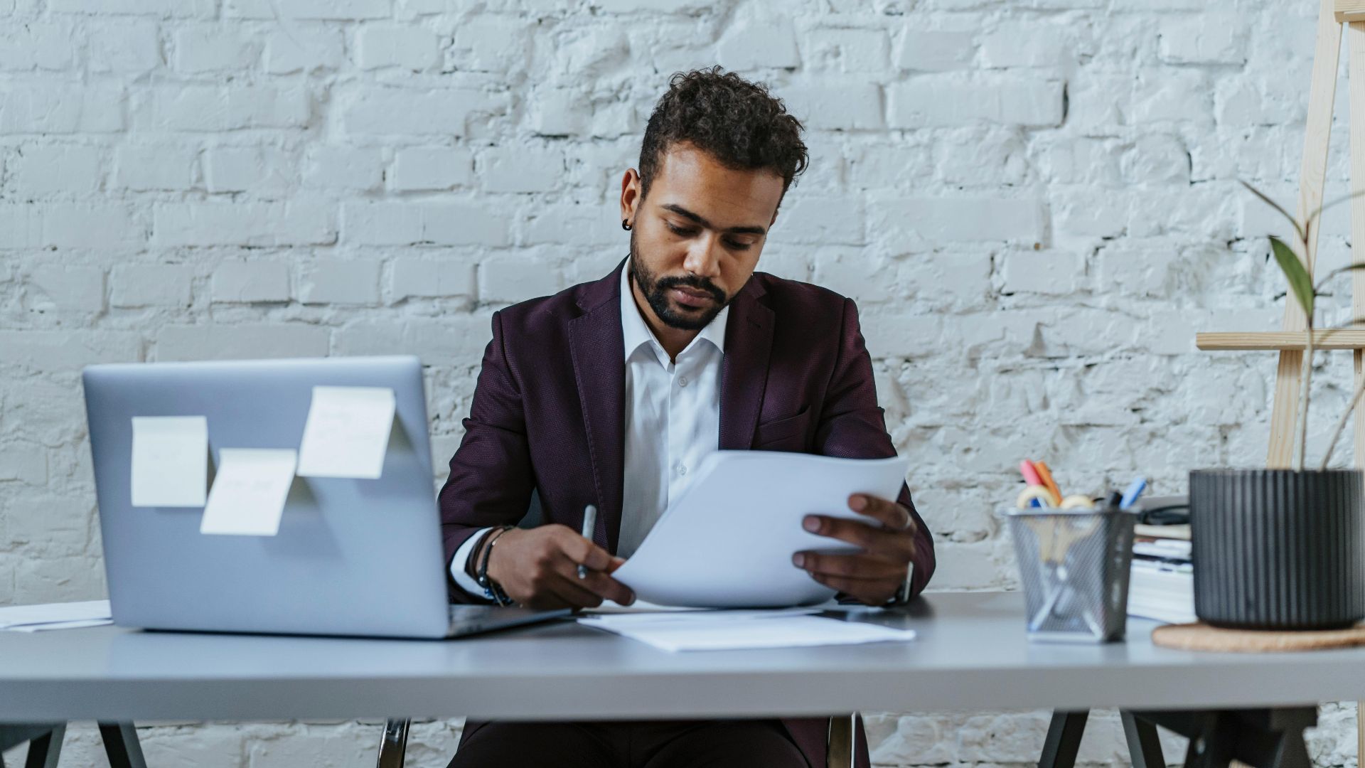 A professional man reviews documents in a modern office setting, focused on his work.
