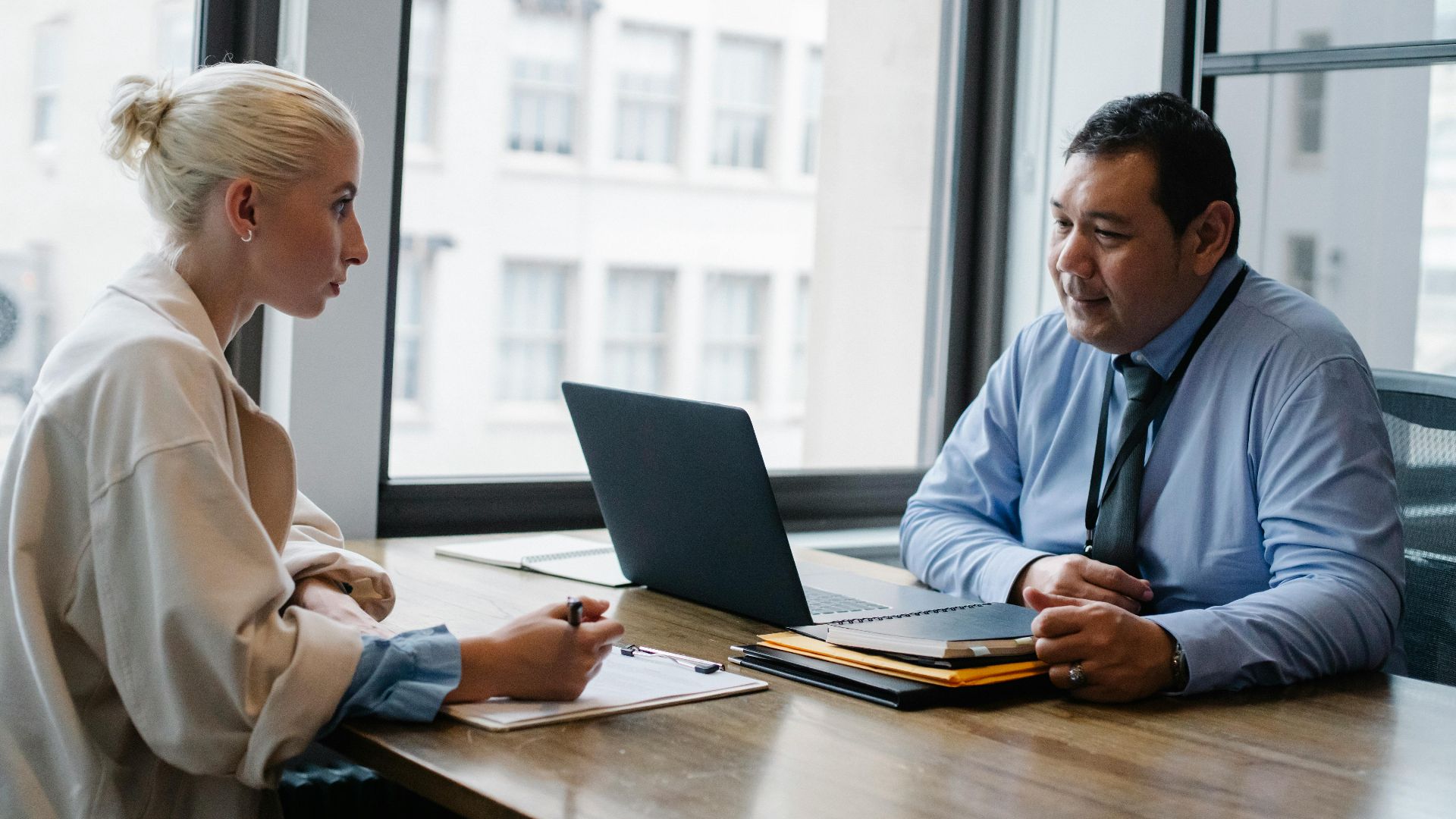 Ethnic boss asking question to female candidate filling information form on clipboard during hiring meeting