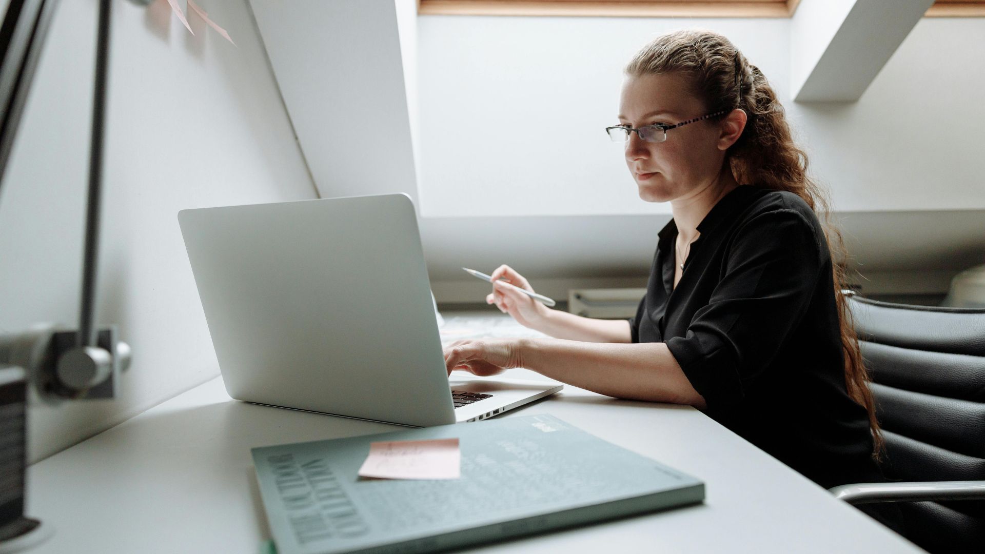 Focused woman working remotely on laptop in modern office setting