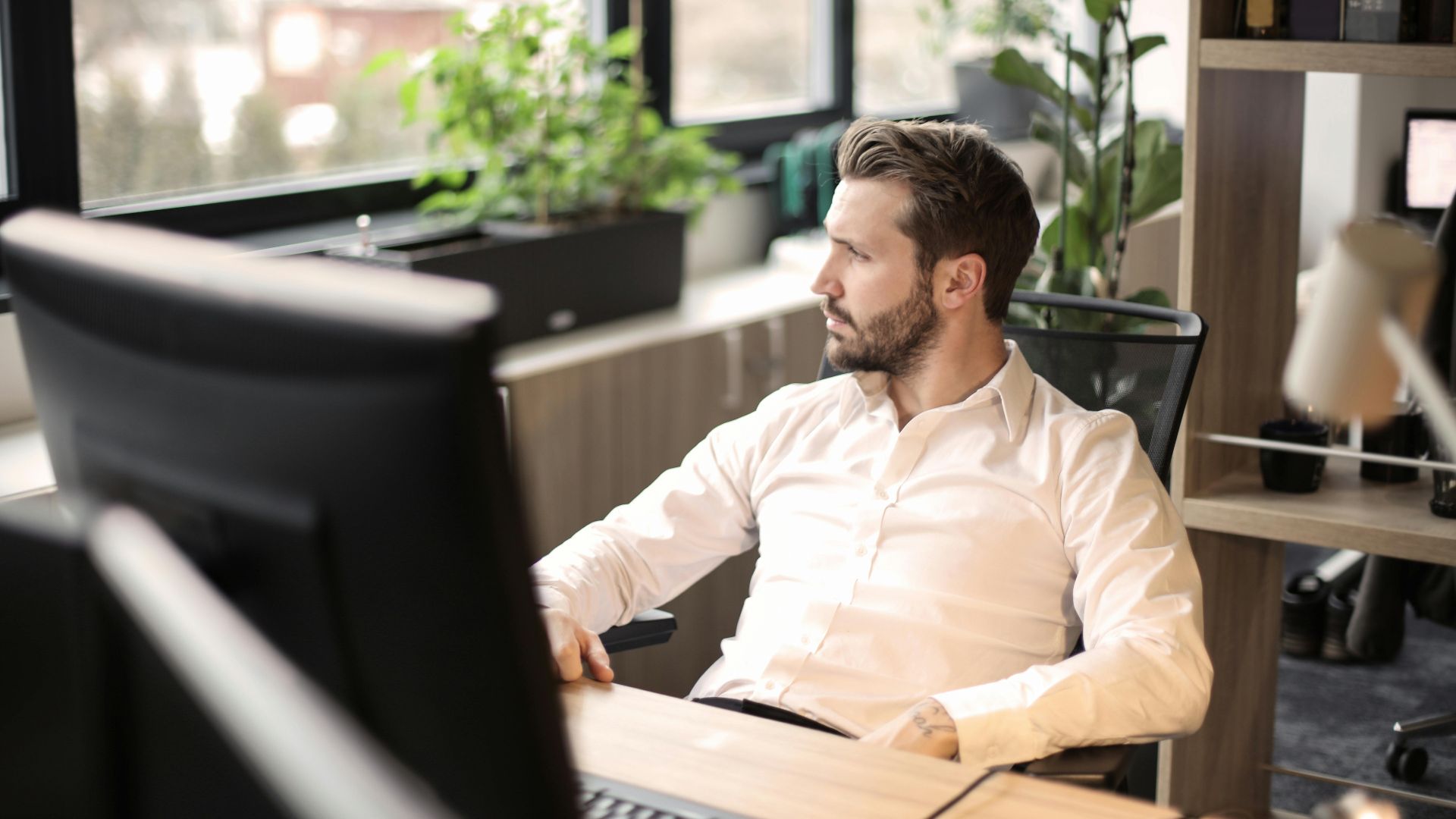 Man in white shirt working in a modern office with natural light.