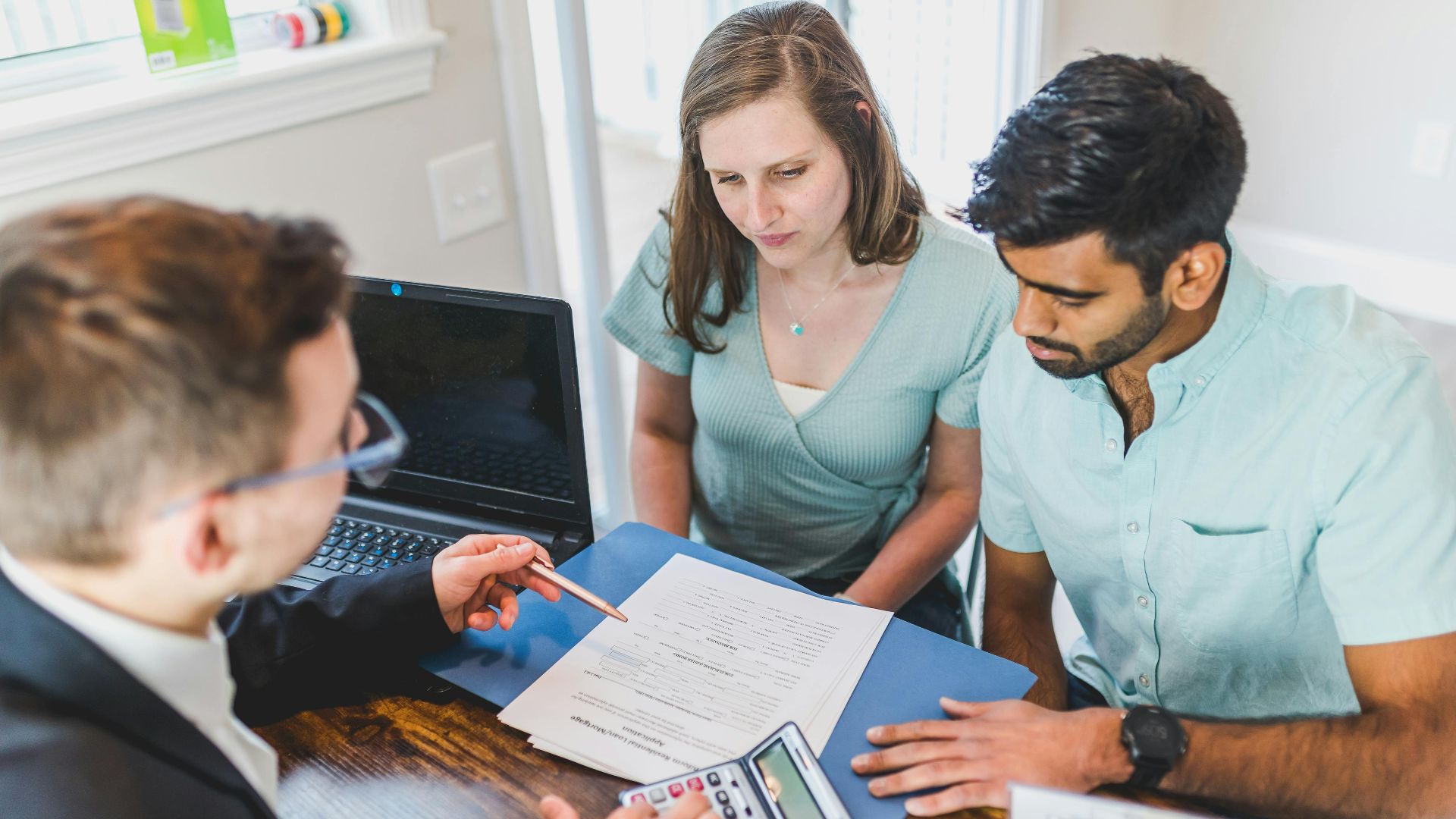 Young couple meeting with real estate agent to discuss property purchase.