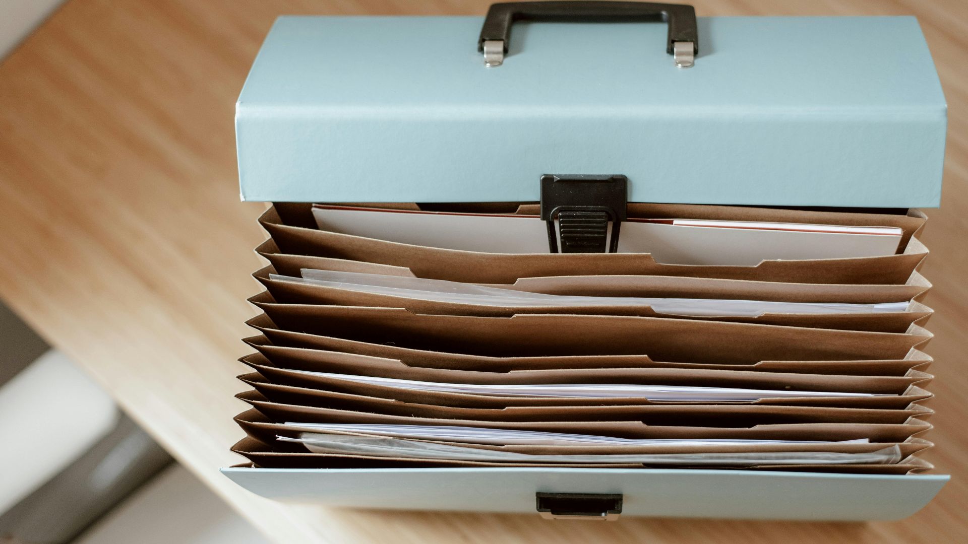 From above of briefcase for documents with papers placed on wooden table in daytime